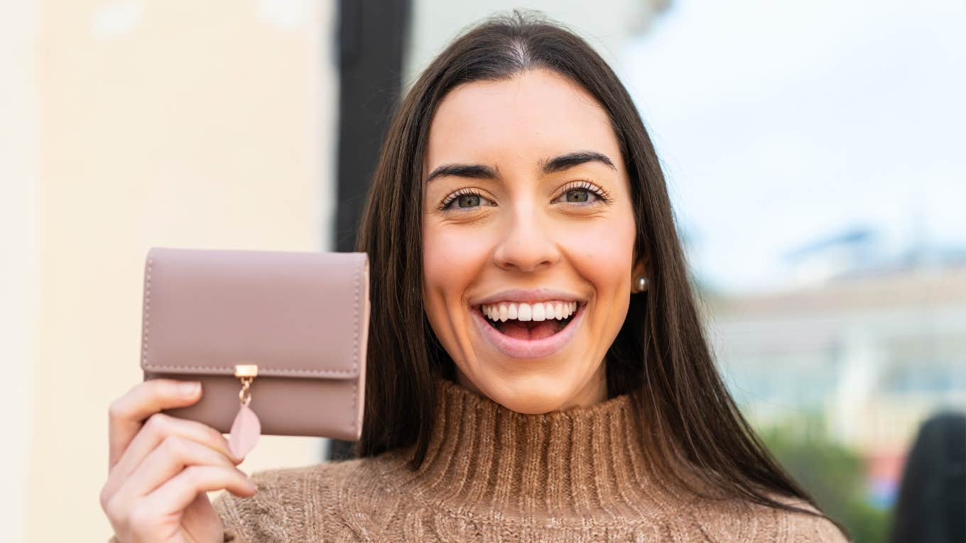 Frugal Habits Brilliantly Cheap People Use That Can Actually Get You On The Right Track frugal woman holding up wallet smiling