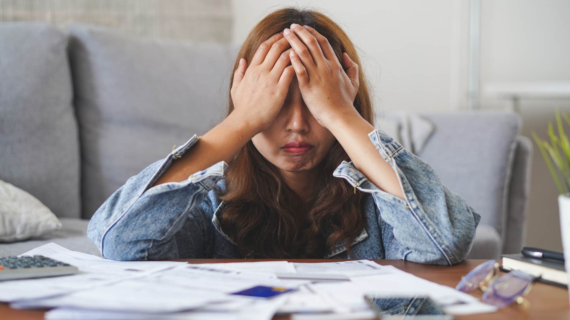 Stressed woman doing bills after overusing credit cards.