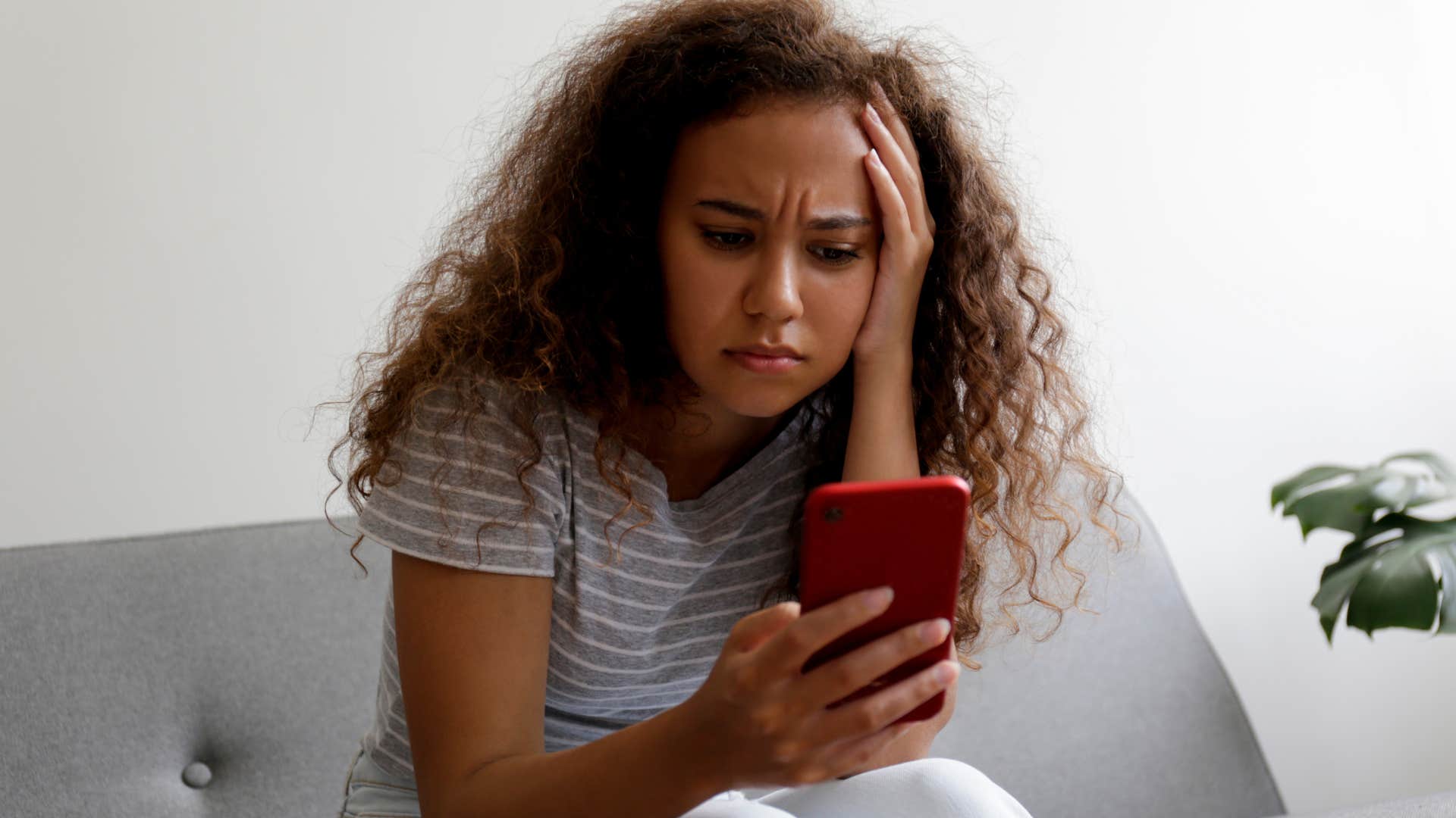 Woman reading all the news headlines looking stressed on her couch.