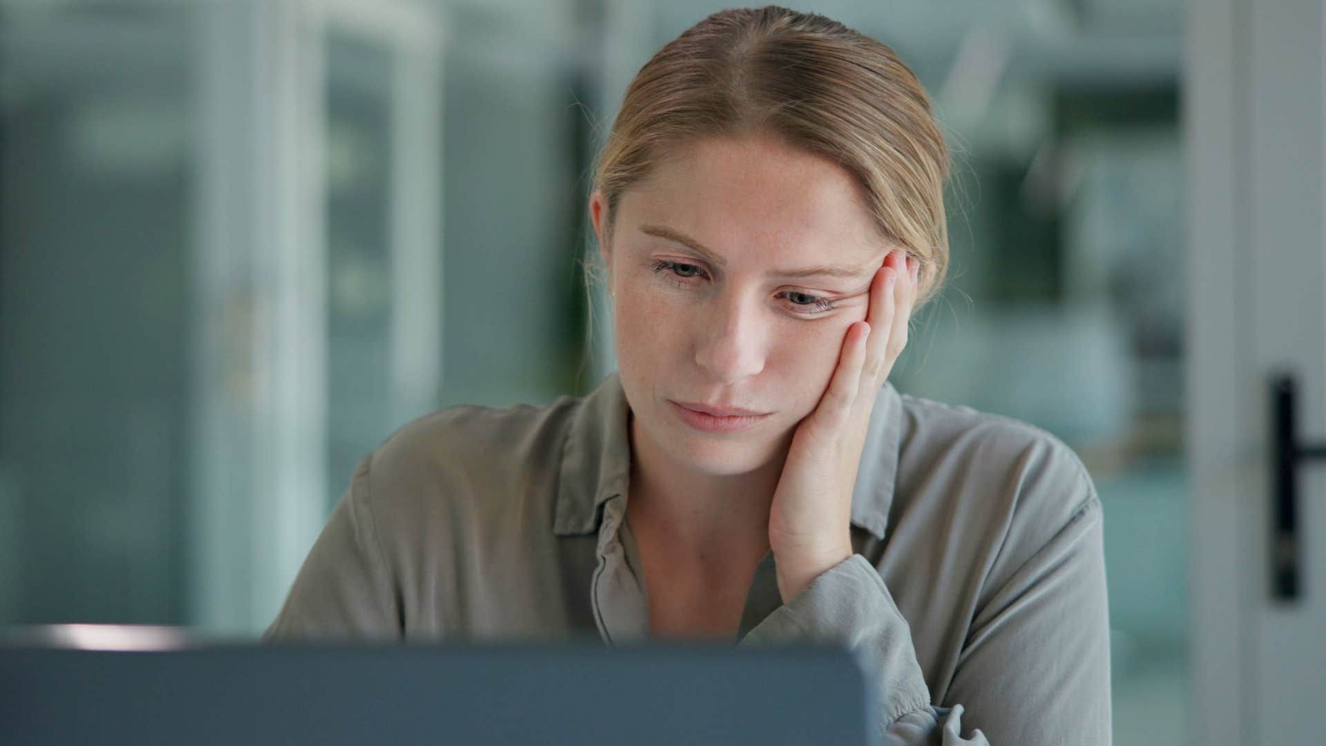 Woman struggling with procrastination looking at her laptop.