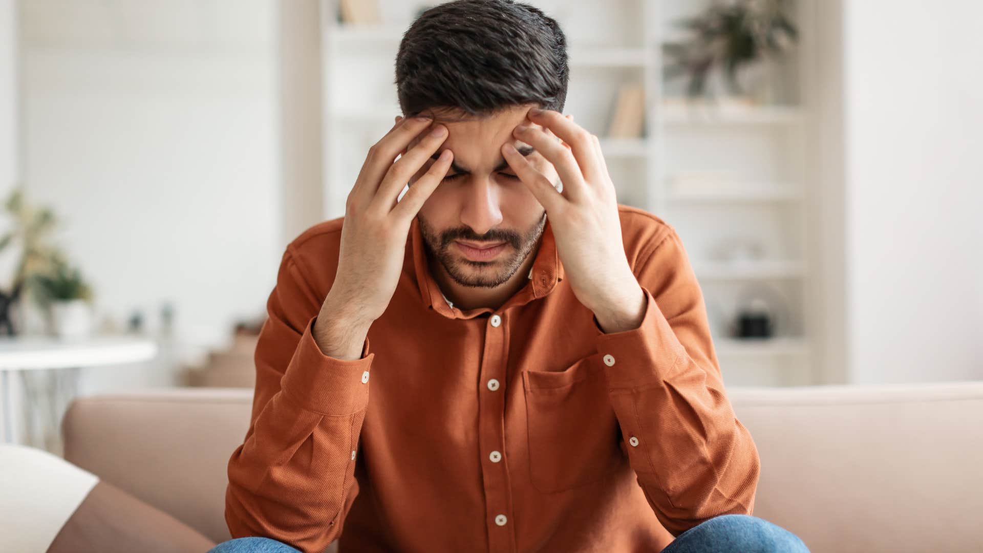 Man with reactionary stress relievers holding his head in his hands.