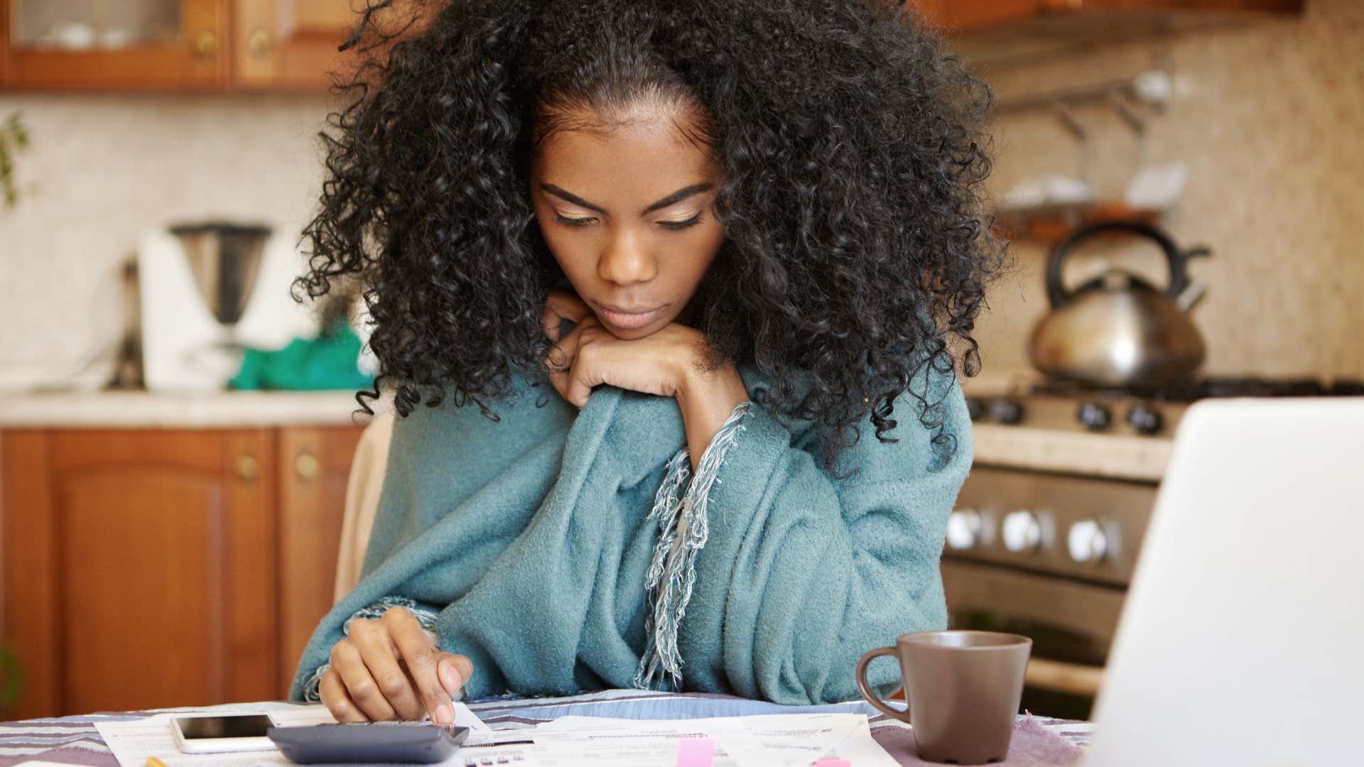 woman feeling financially unstable doing bills in her kitchen