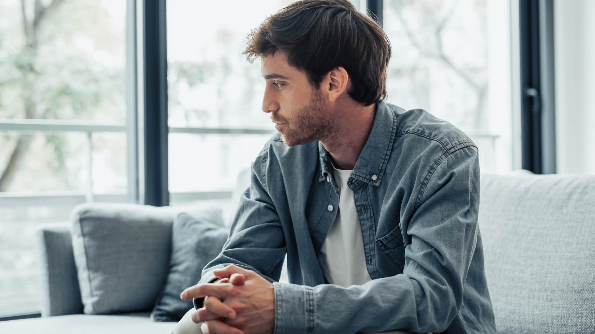Man living alone looking sadly out a window.