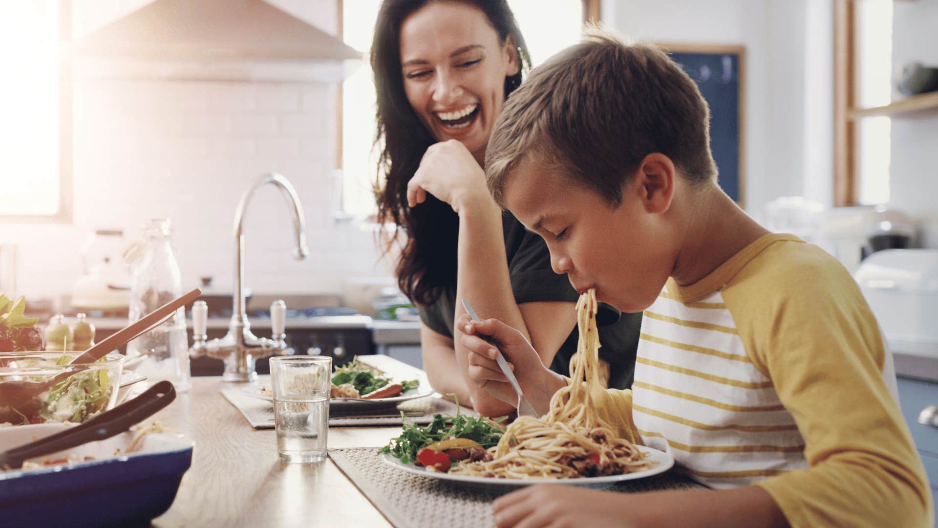 Young boy and his mom having a family dinner at the table.