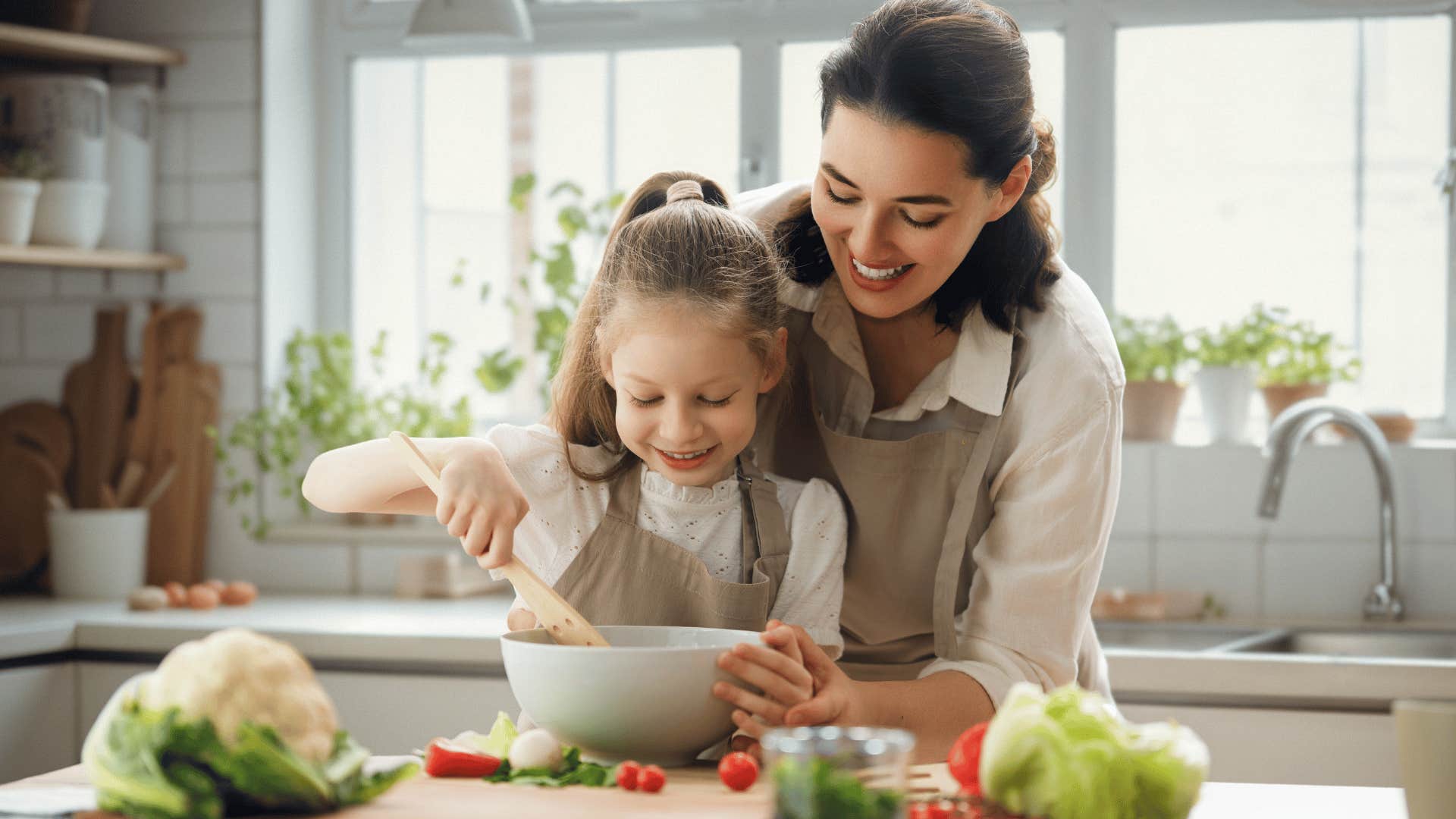 Mother cooking with fruits and vegetables in the kitchen with her daughter.