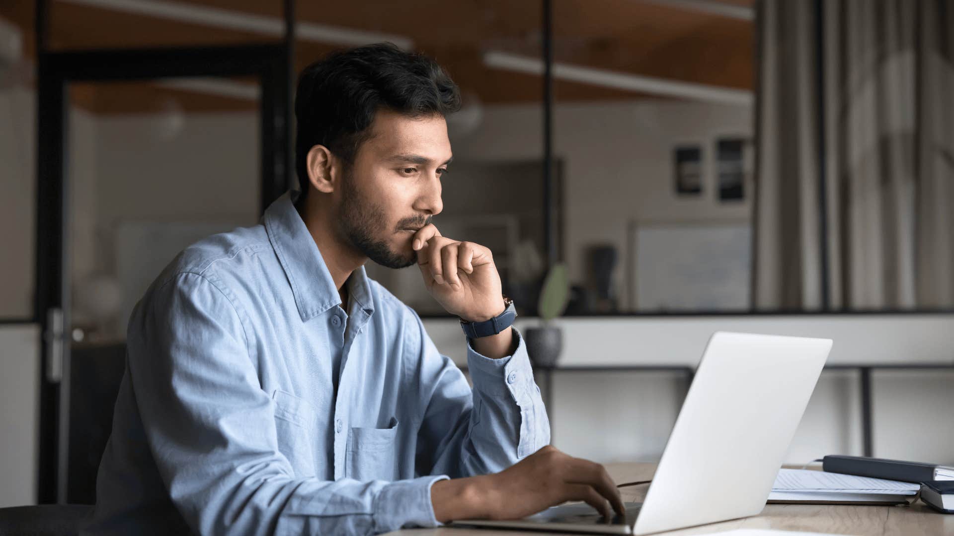 man working on laptop thinking about life's questions