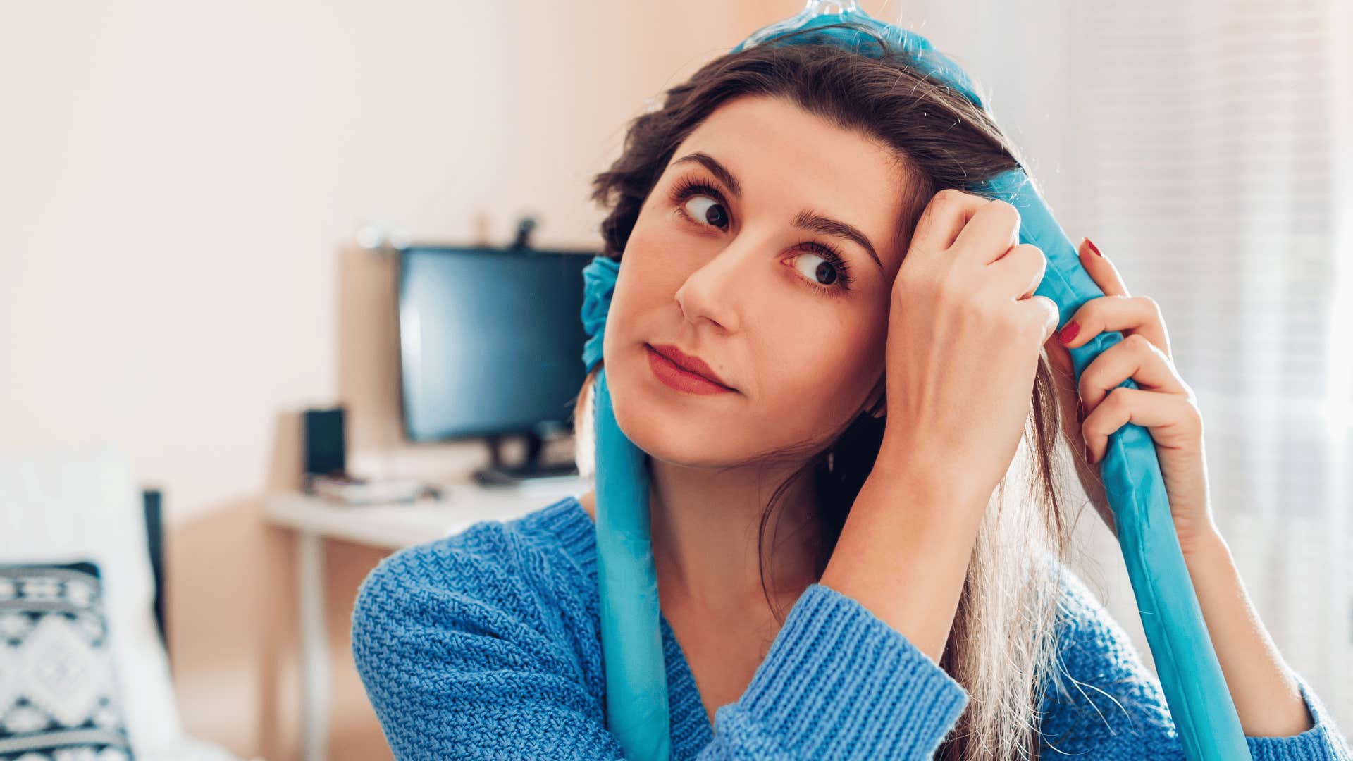 woman engaging in self-care routine as she puts roller in her hair 