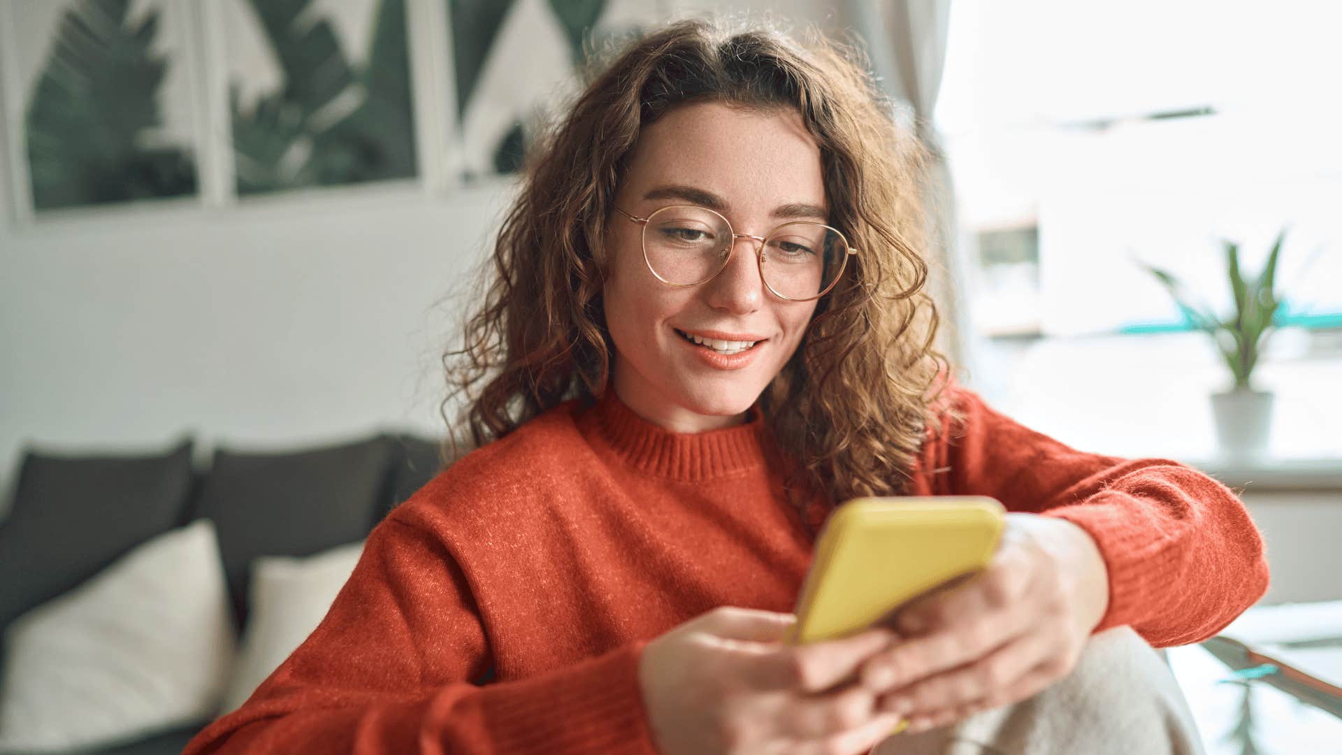 woman on her phone smiling while she unfollows unhelpful or toxic accounts