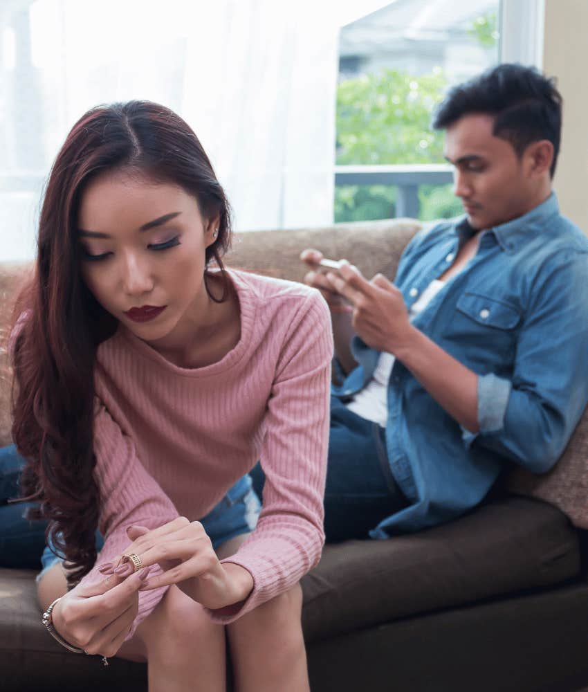 Woman takes of wedding ring while man plays with phone