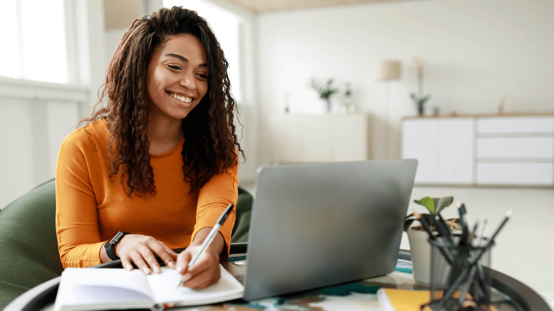 woman who knows millennial money hacks smiling at laptop 
