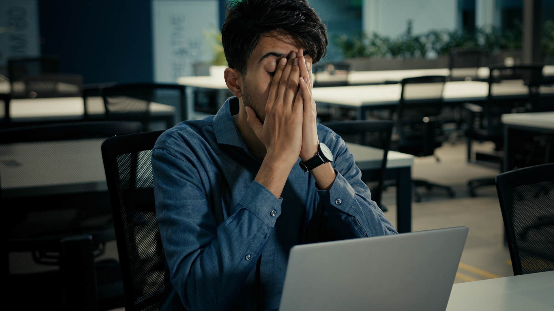 burnt out millennial man holding his head