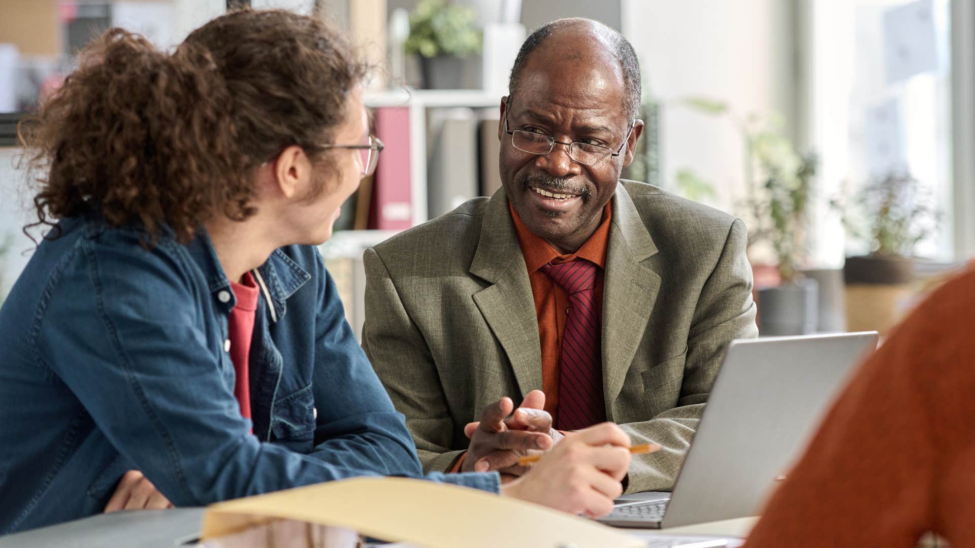 Baby boomer man talking to his young co-worker about applying for jobs.