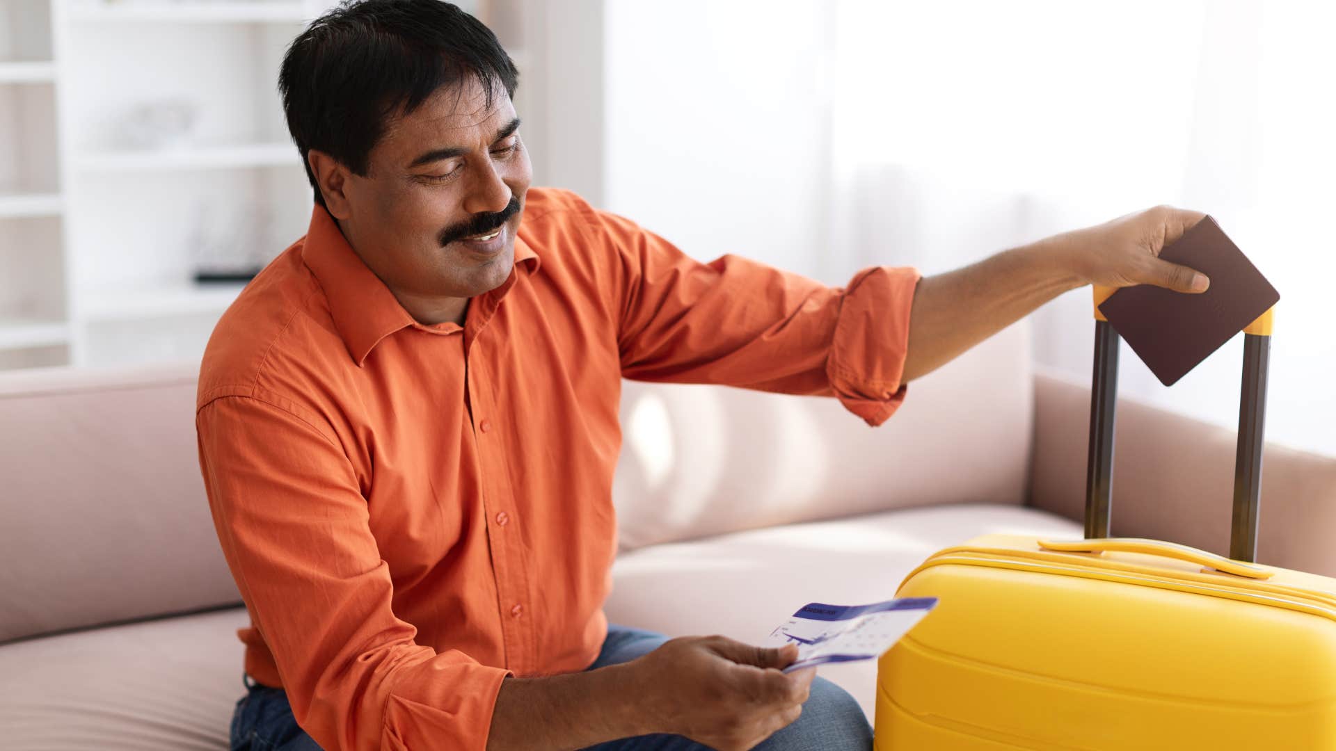 Man without a digital boarding pass sitting next to his luggage at home.