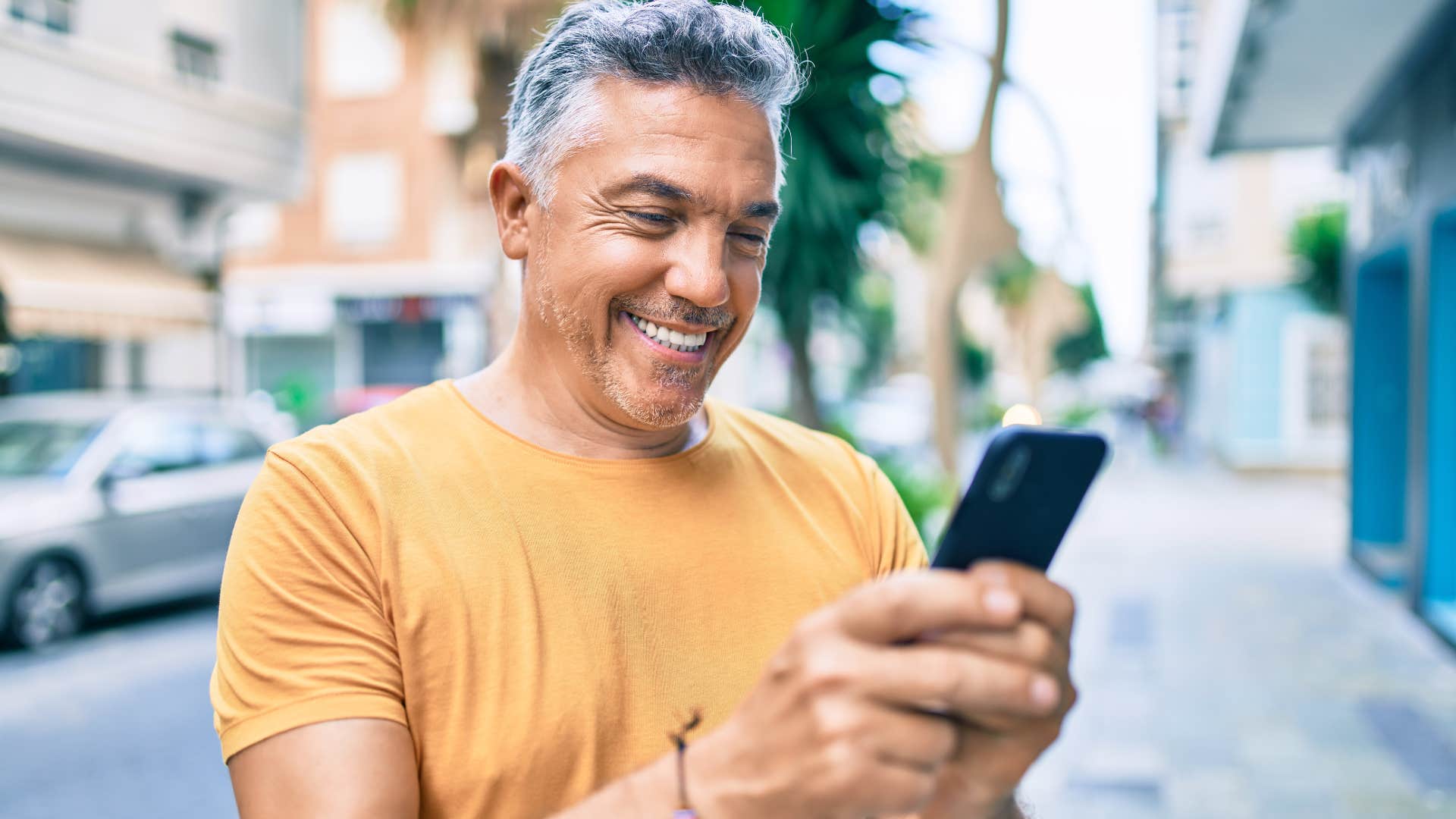 Baby boomer man ordering an Uber on his phone outside.