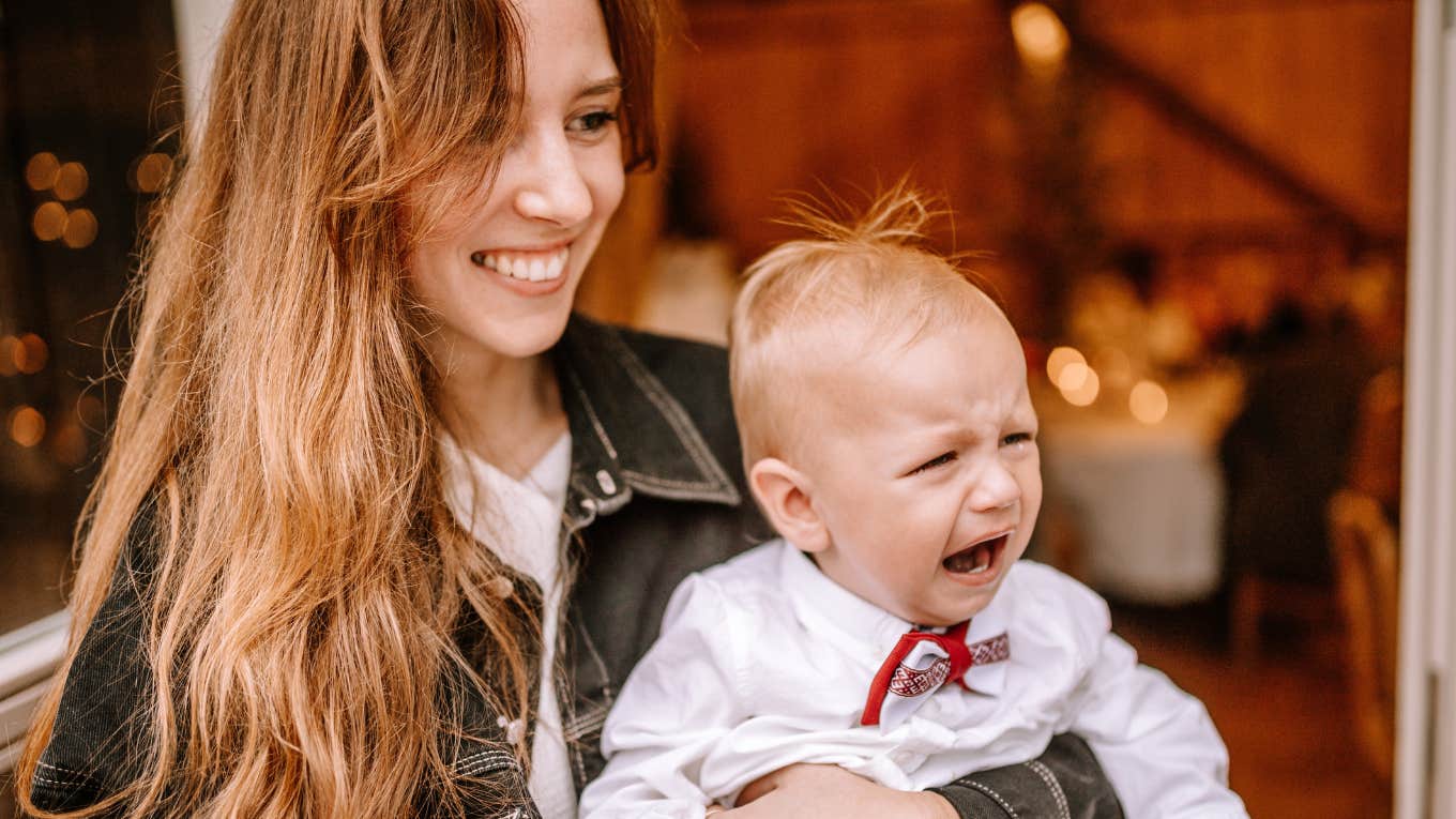 Mom holding her crying baby at her friend's birthday party