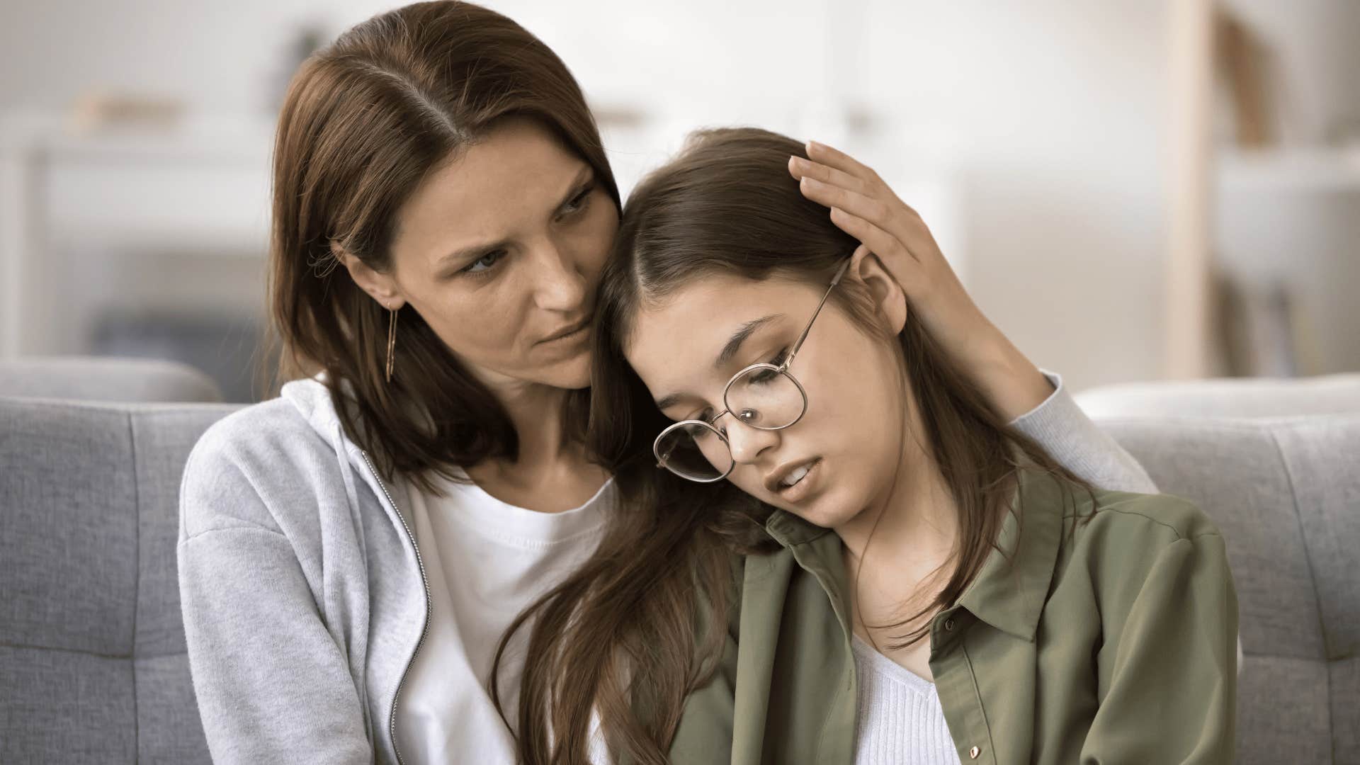 mom listening to her daughter and stroking her hair in comfort