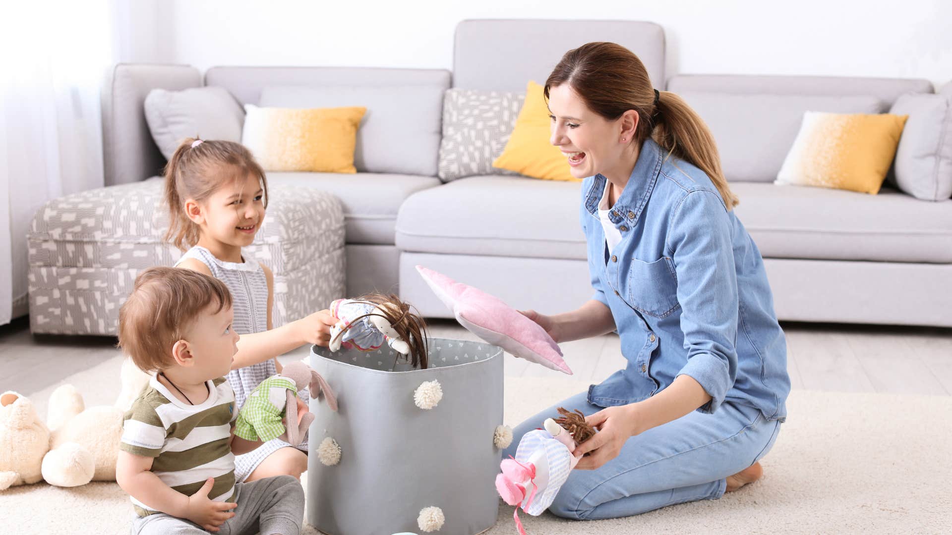 mother playing with young children cleaning up toys
