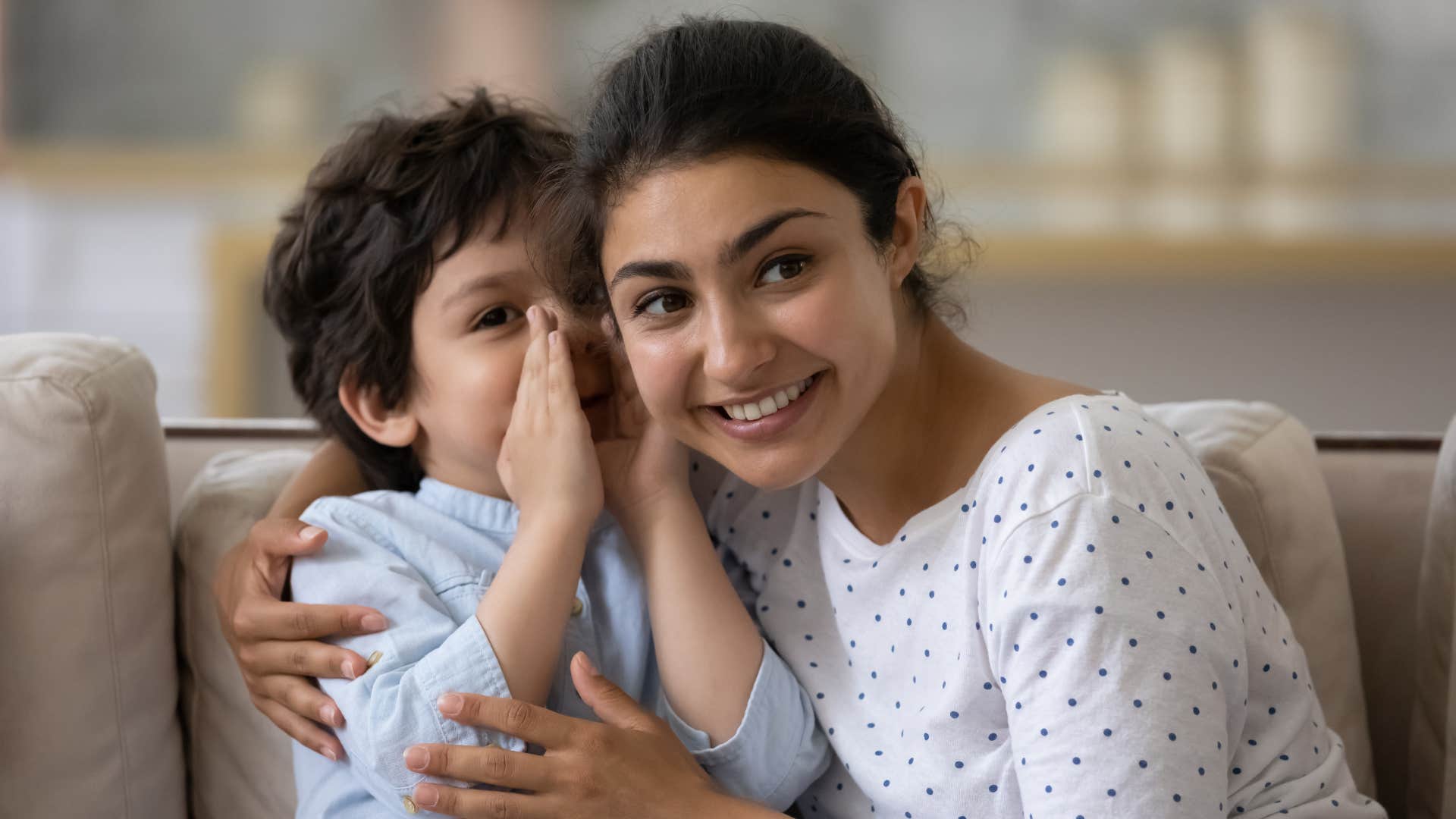 little boy whispering in mother's ear