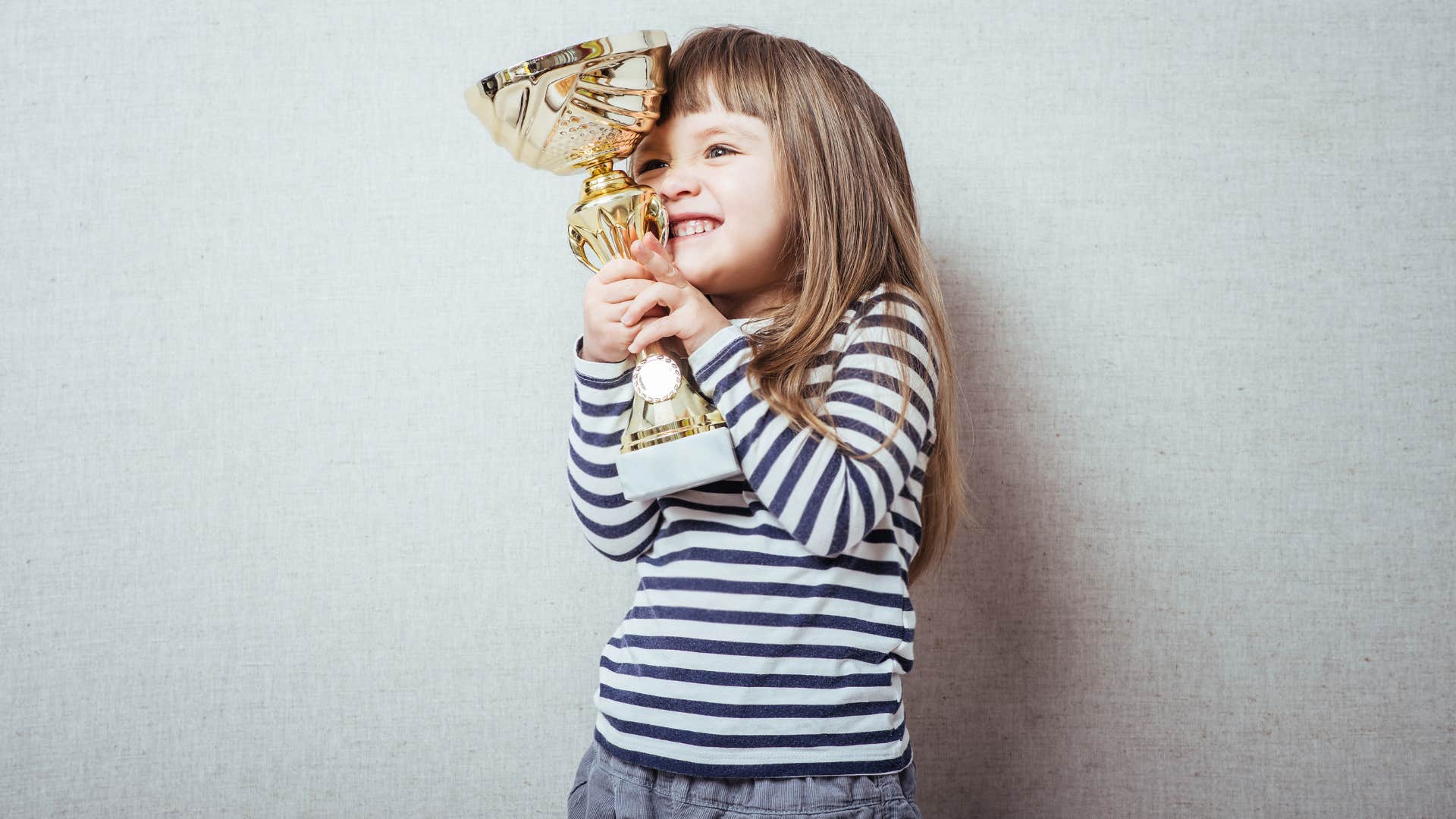 young girl holding a trophy smiling