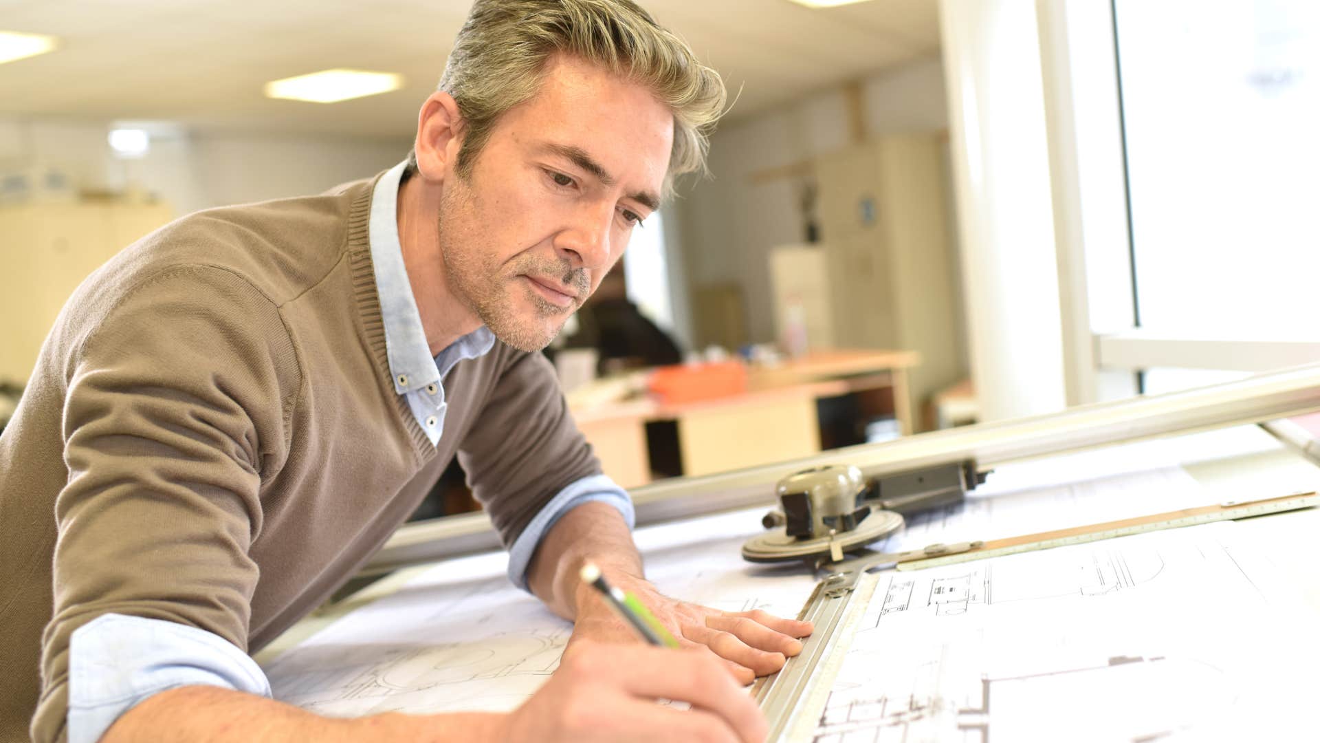 Traditional cartographer drawing at a desk.