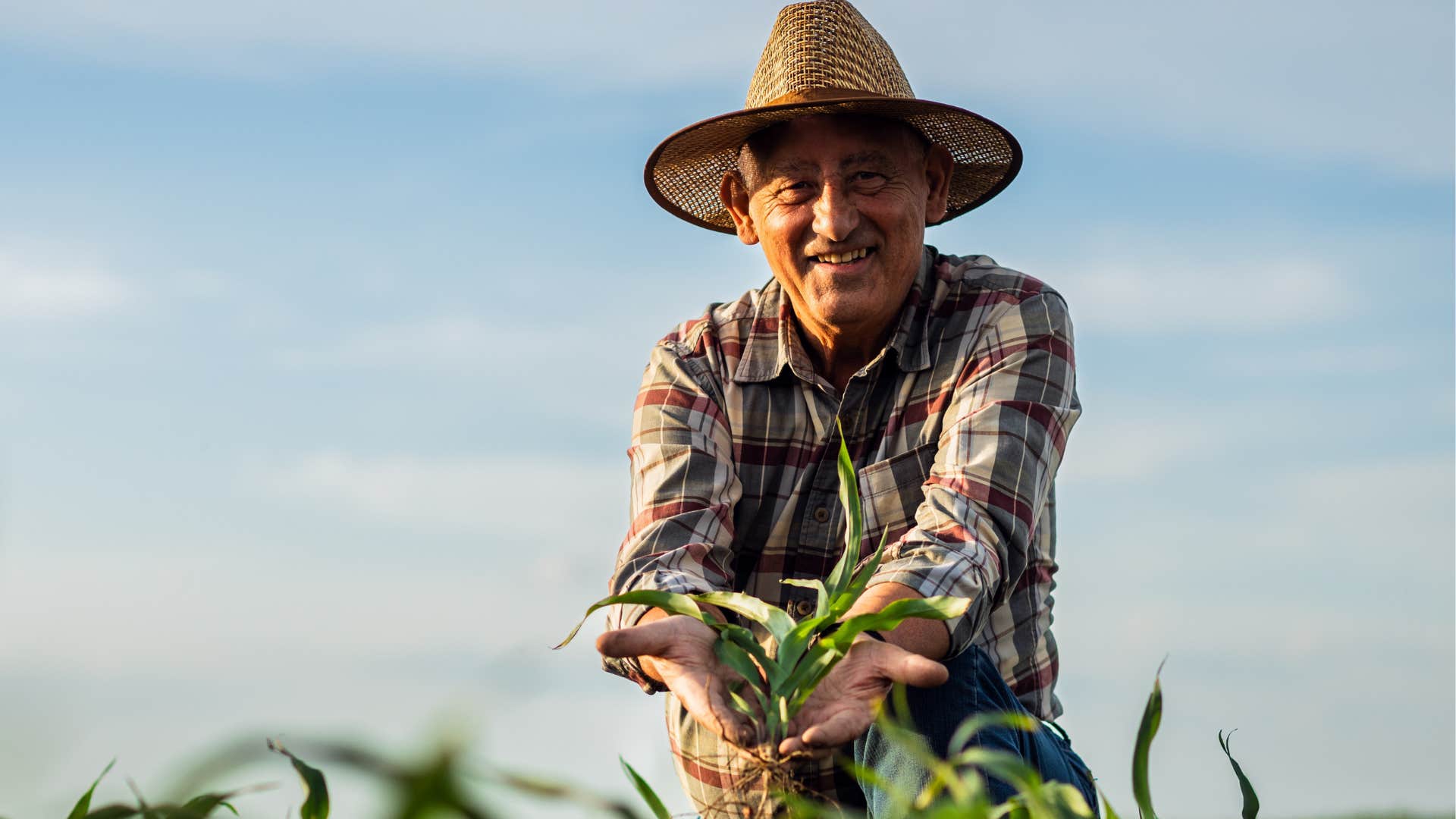 Farm worker smiling and standing in his field.
