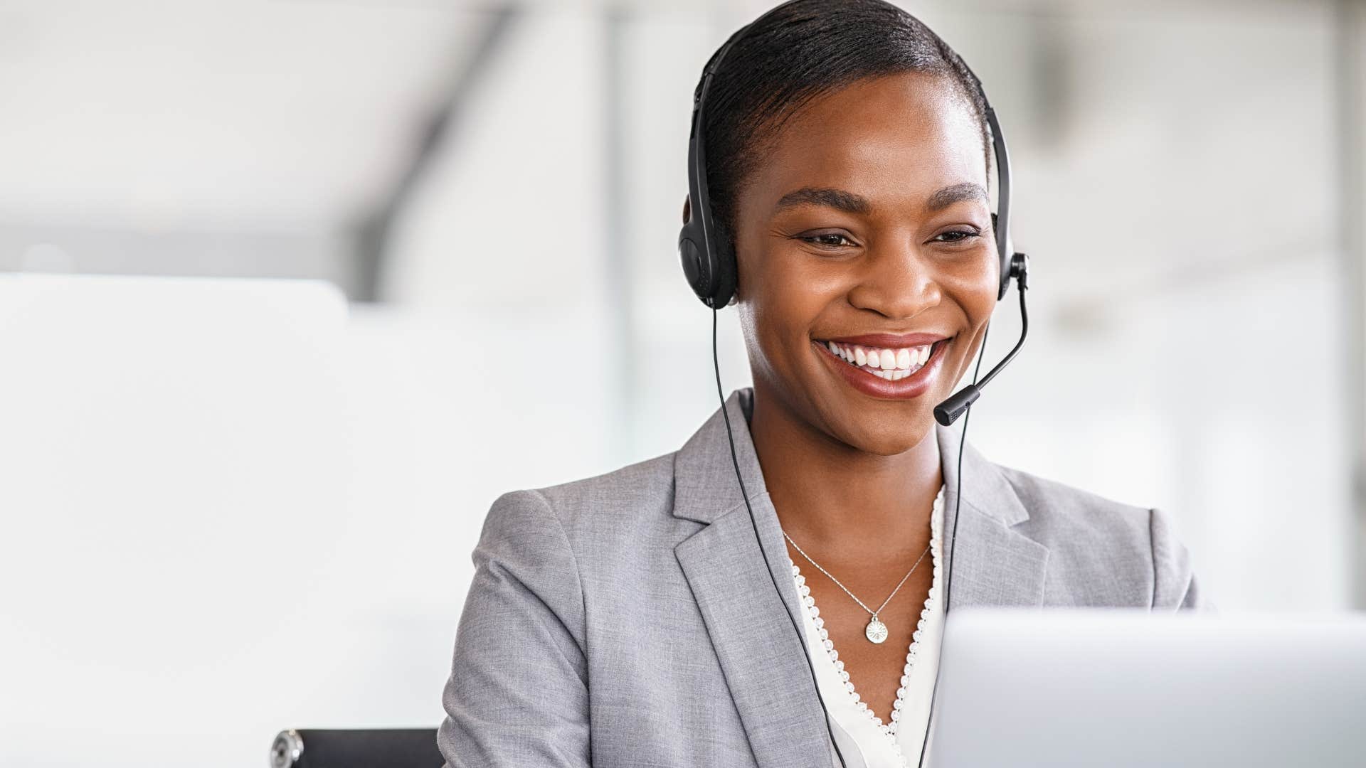 Telemarketer smiling and talking to someone on her laptop.