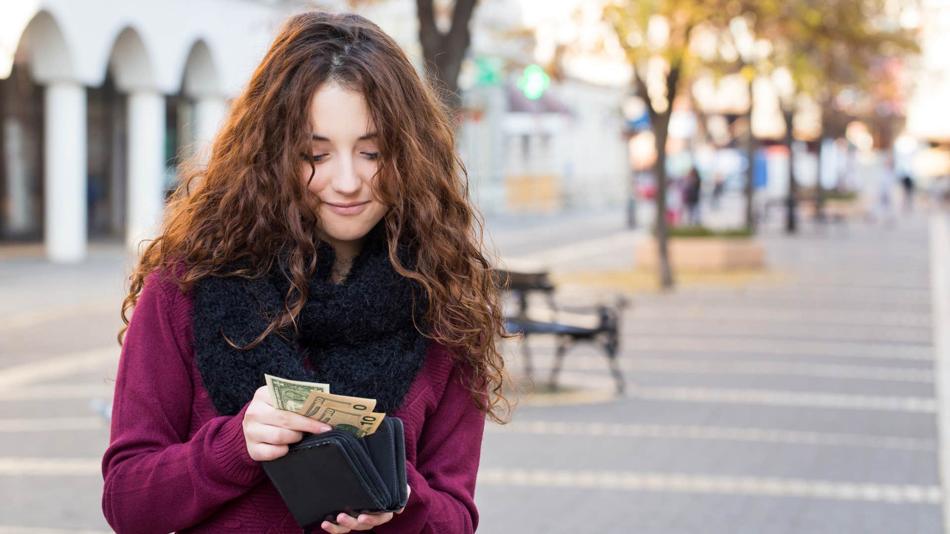 woman in red shirt counting money as her financial priorities have shifted