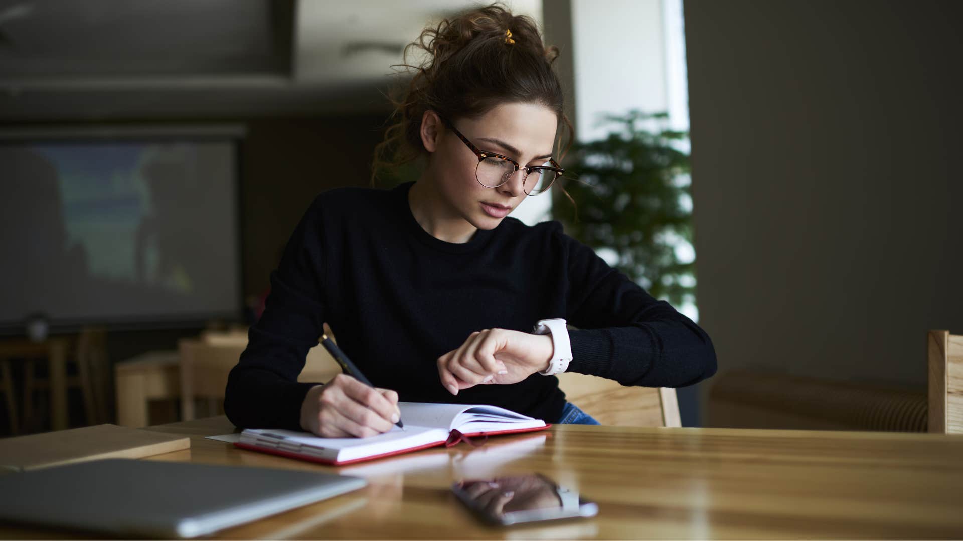 woman in black shirt with limited time checking watch while working