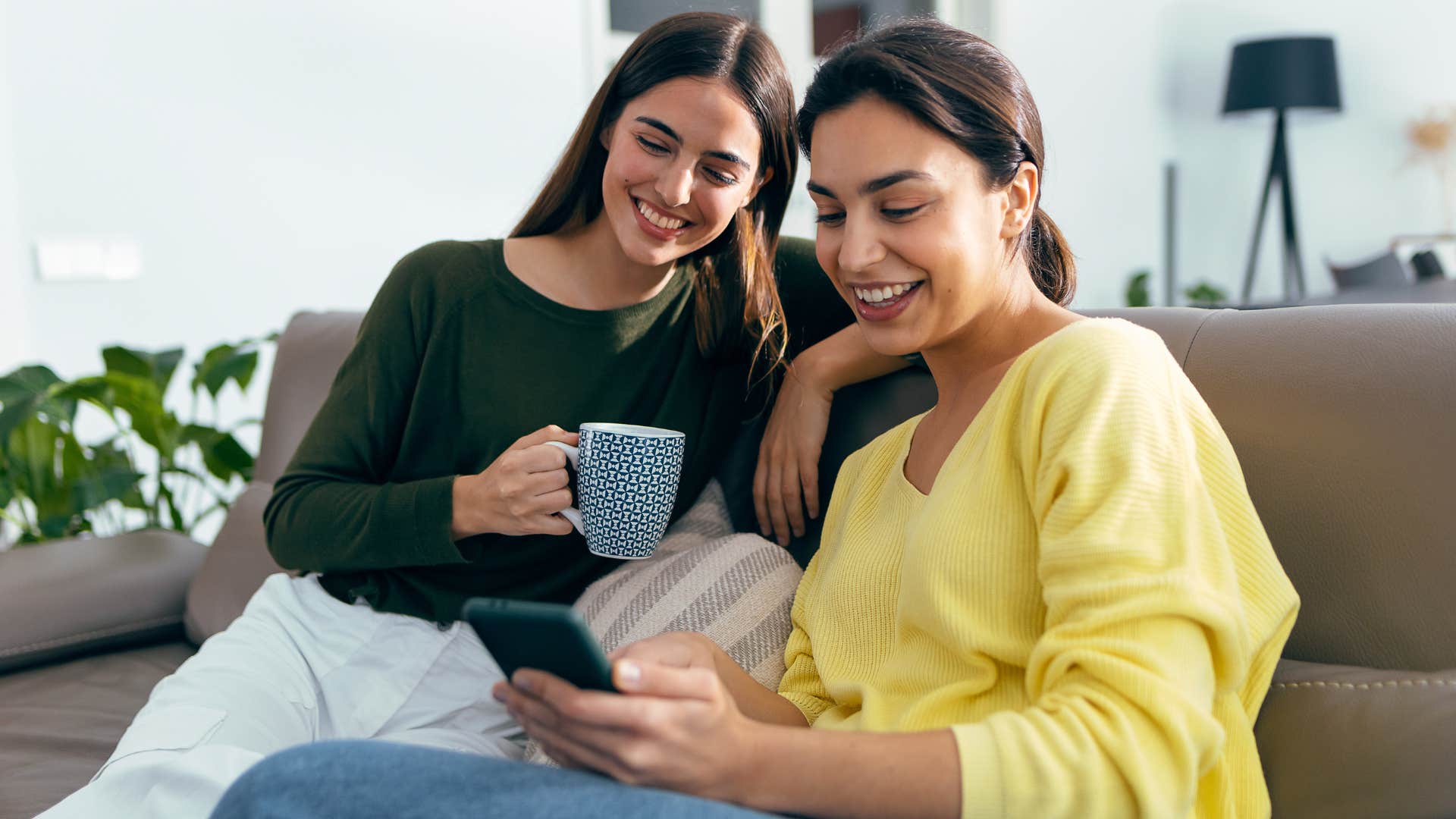 two women who shrunk their social circle hanging out together while looking at a phone