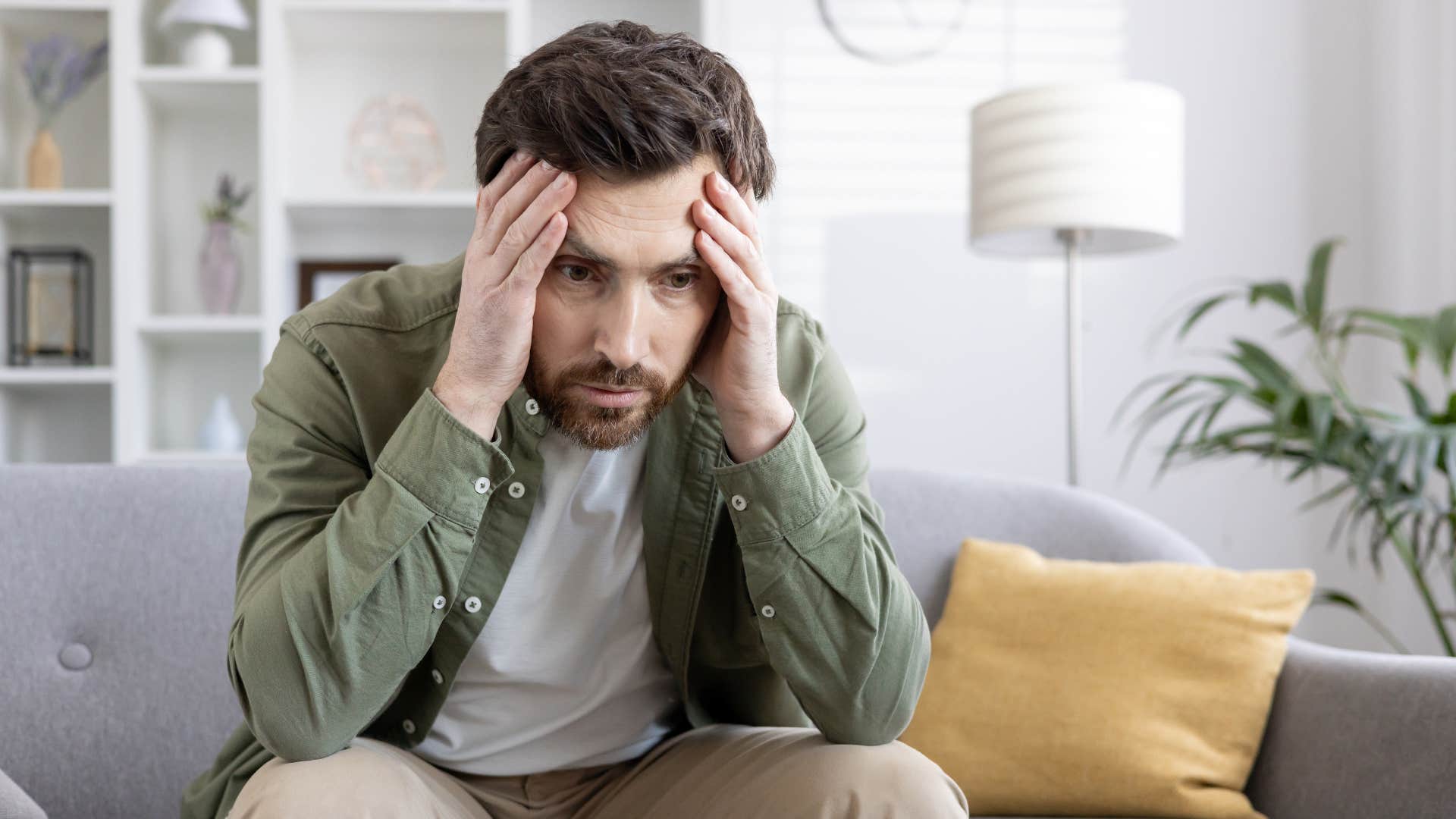 man who lost his motivation clutching head as he looks down feeling distressed