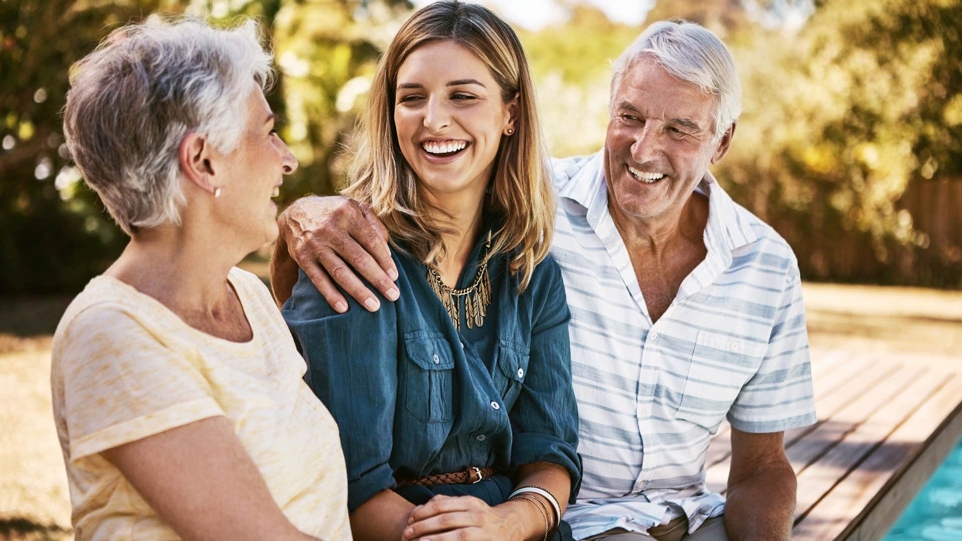 Woman whose adult autonomy is respected smiling in between her parents.