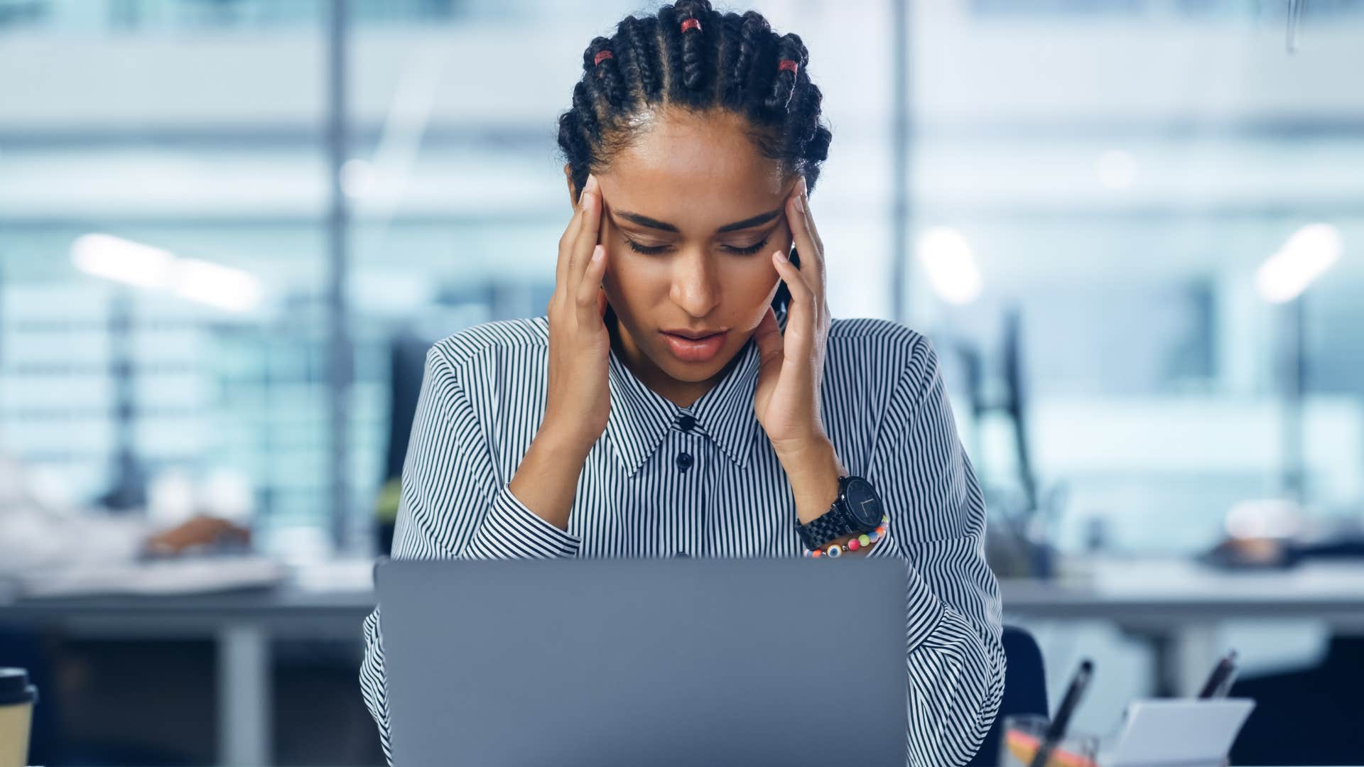 burnt out woman holding her head in the office