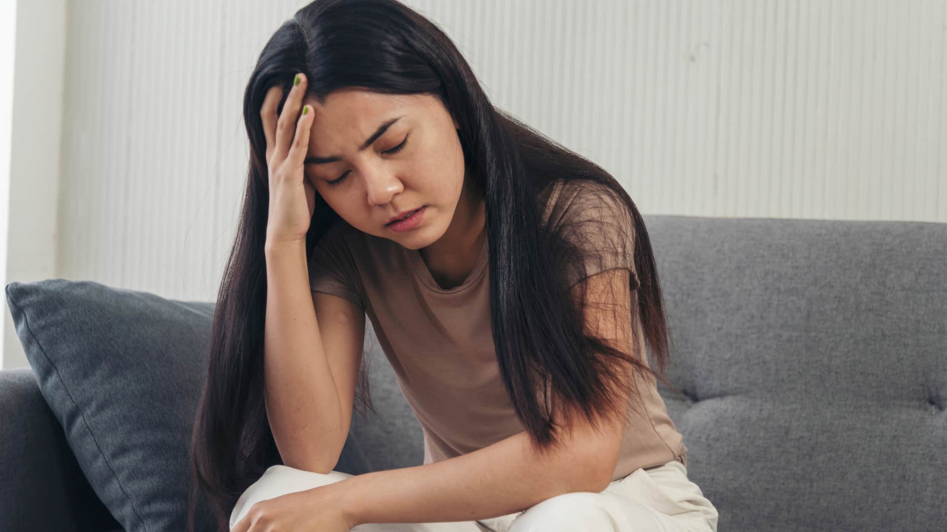 woman holding her head and overthinking looking stressed