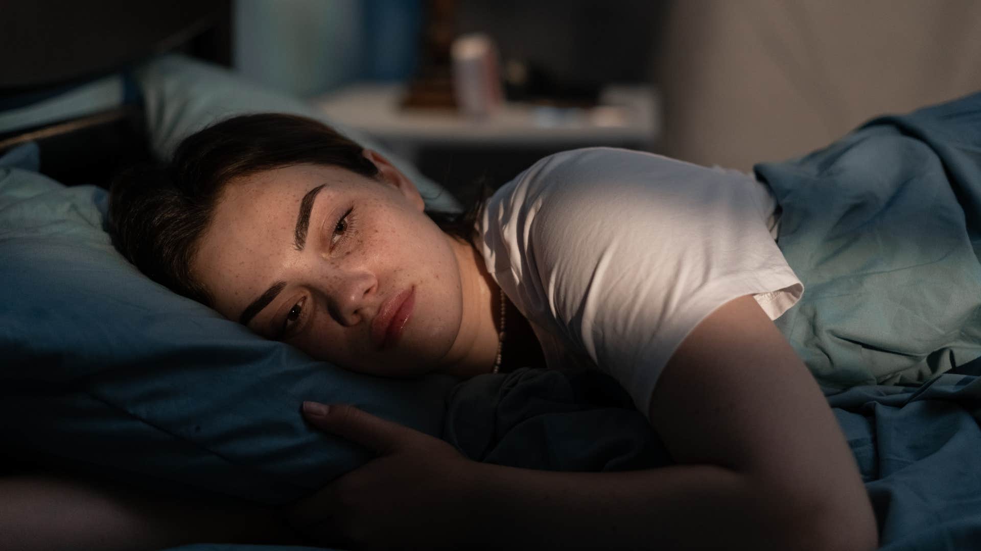 tired woman with a poor nighttime routine laying in her bed