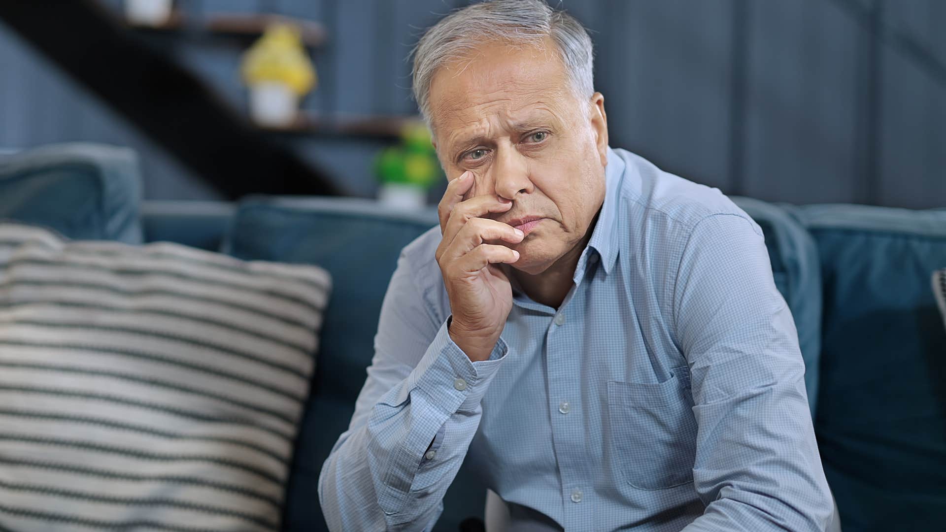 older man experiencing physical changes sitting on his couch