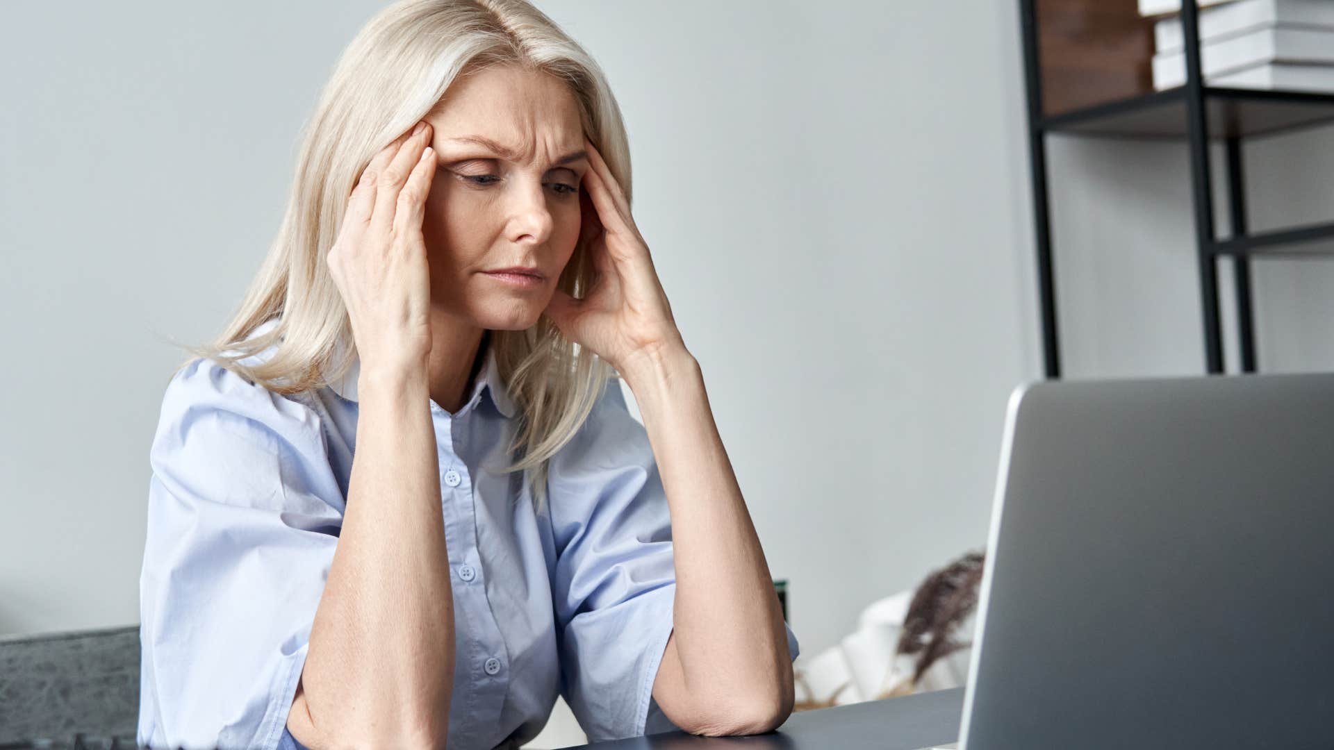Woman who's protective over their independence holding her head in her hands.
