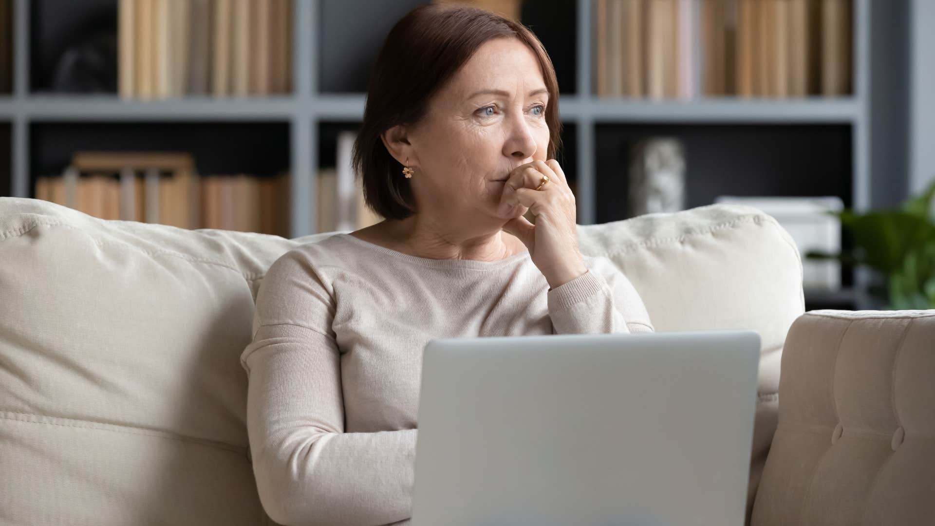 Woman who needs to feel respected looking out a window at home.