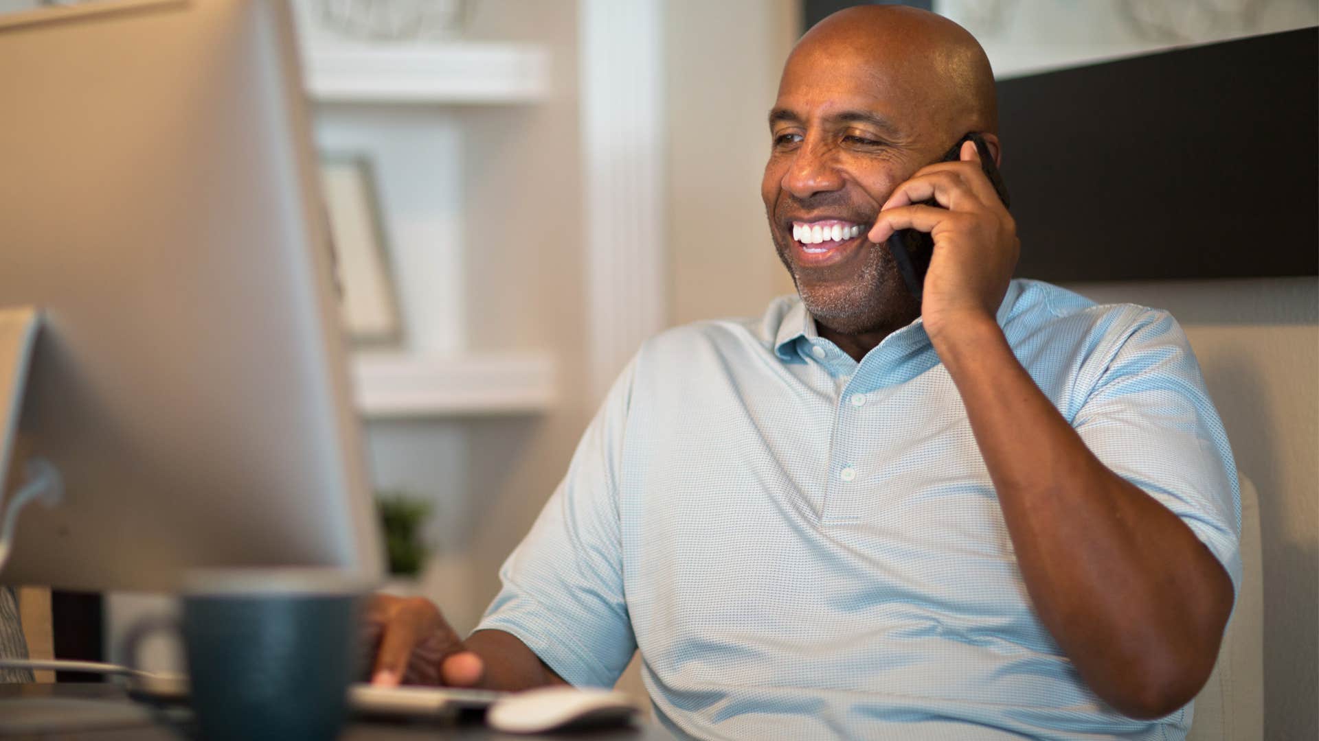 Self-aware man smiling and talking on the phone.