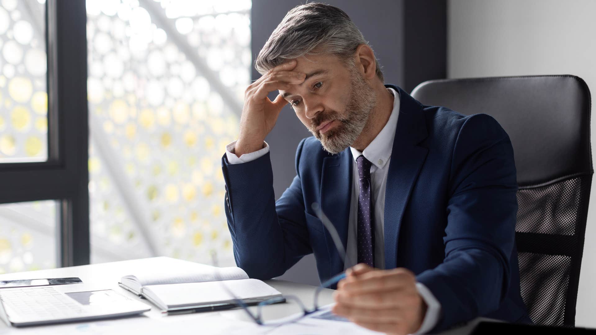 Upset man who knows what they want and need holding his head in his office.