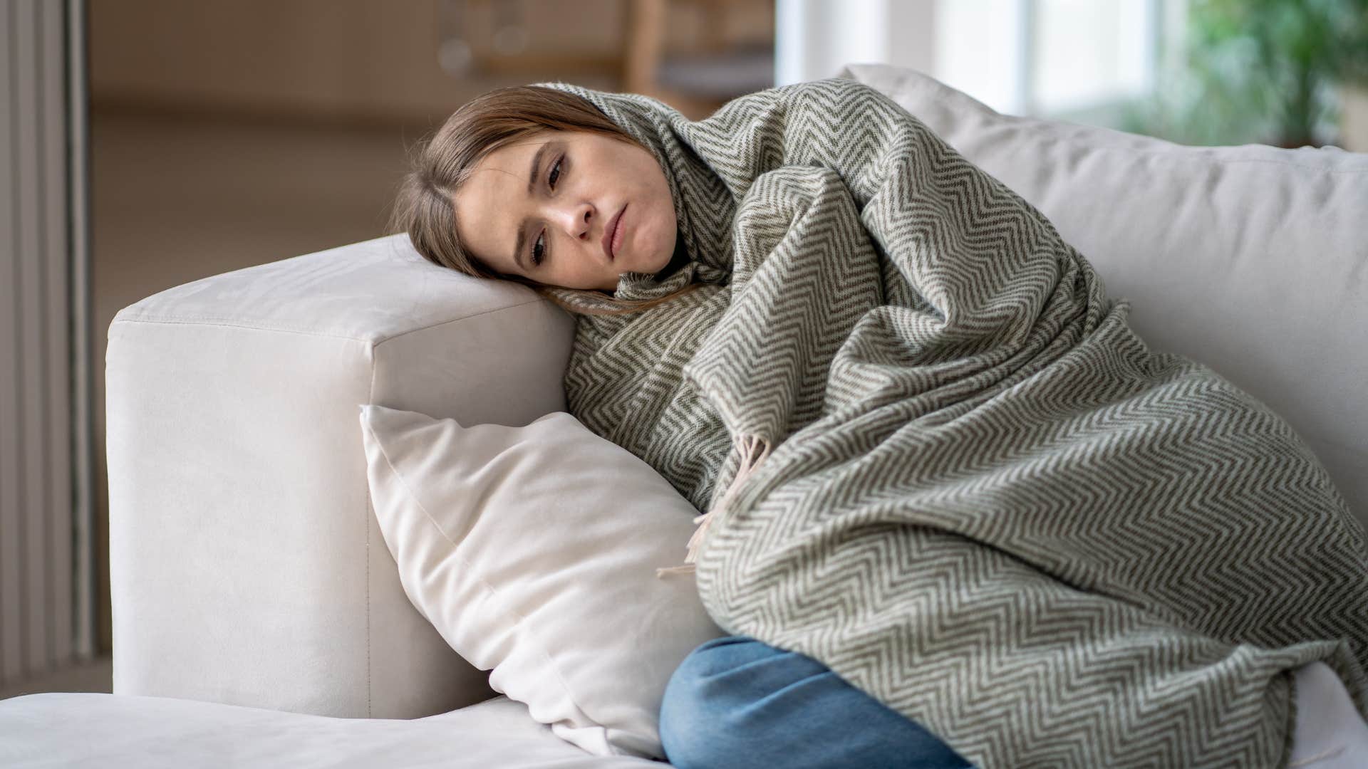 woman sits at home on her couch after having draining conversation