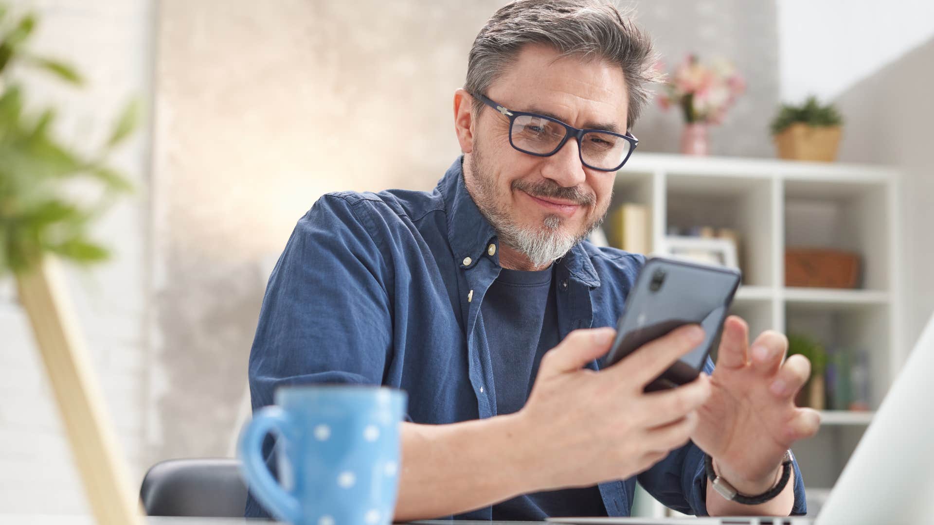 Man who is less open to new experiences smiling at his phone.