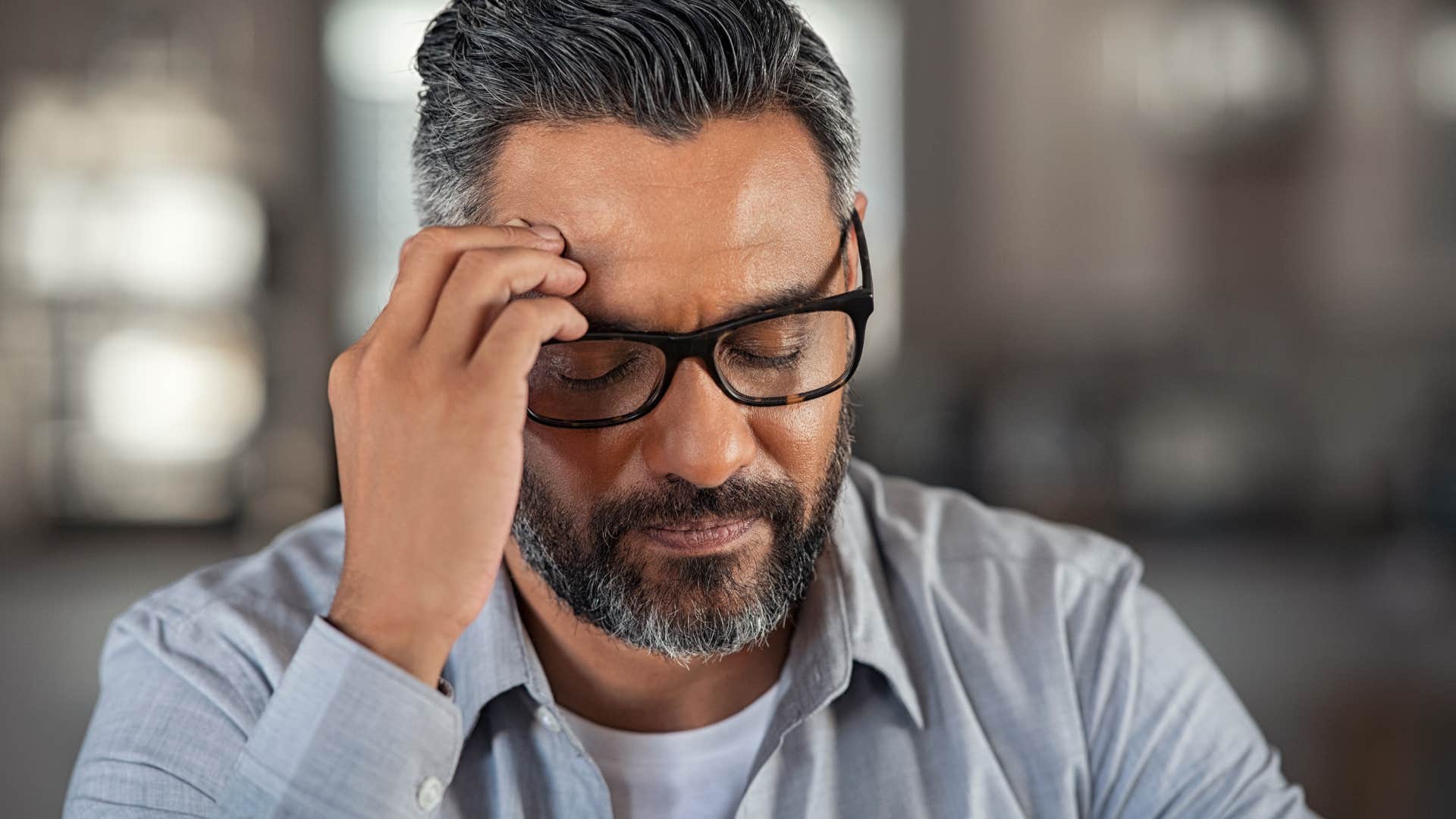 burnt out older man holding his forehead