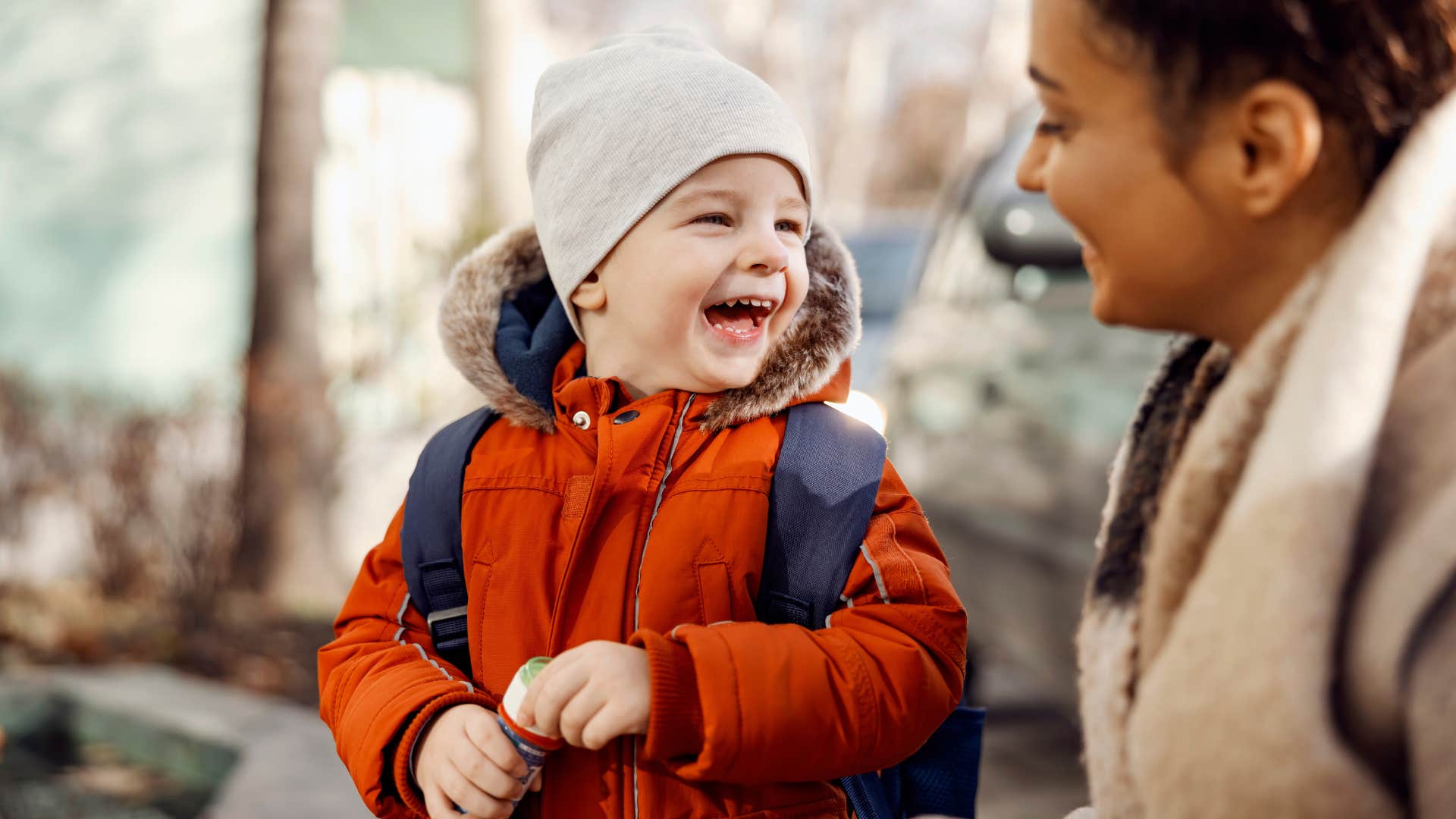 caregiver smiling at a young boy outside