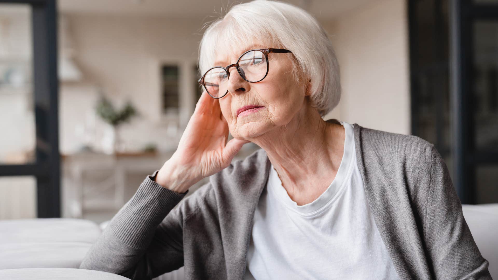 stressed older woman sitting inside staring longingly