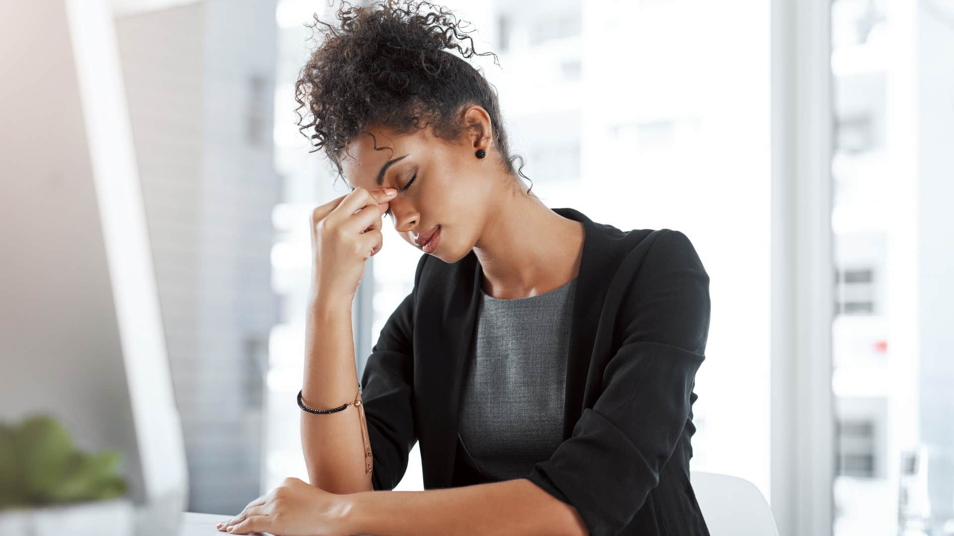 Woman with headaches holding her head at work.