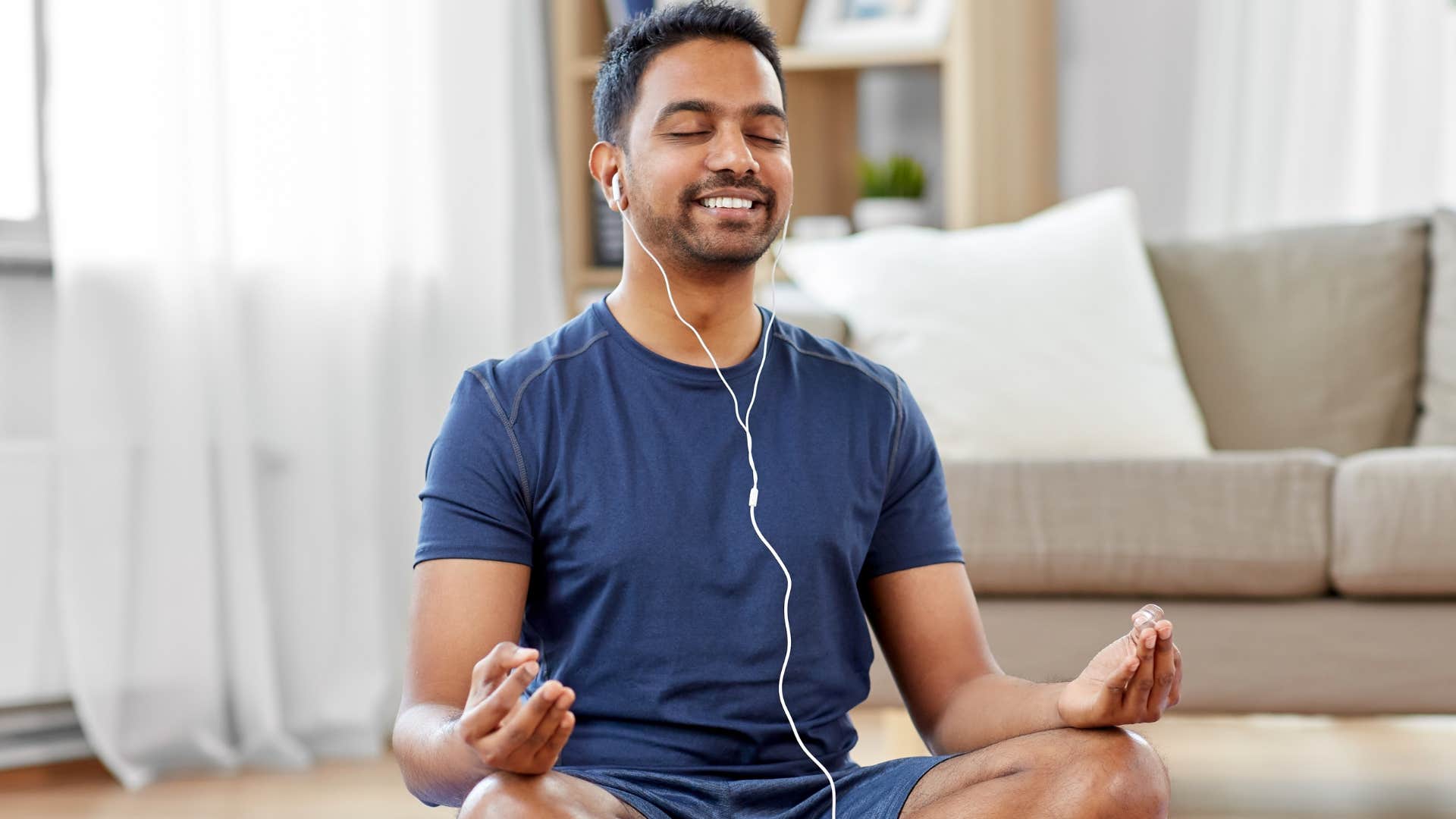 Man with a place for movement in his house meditating with headphones on.
