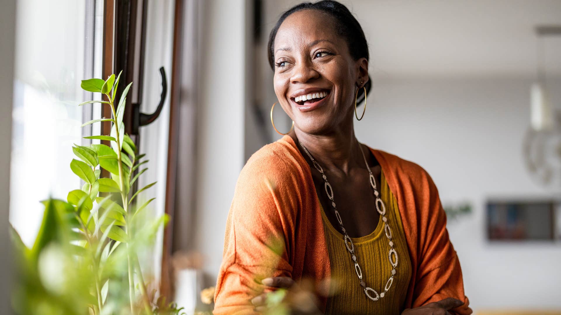 Woman smiling around plants and flowers at home.