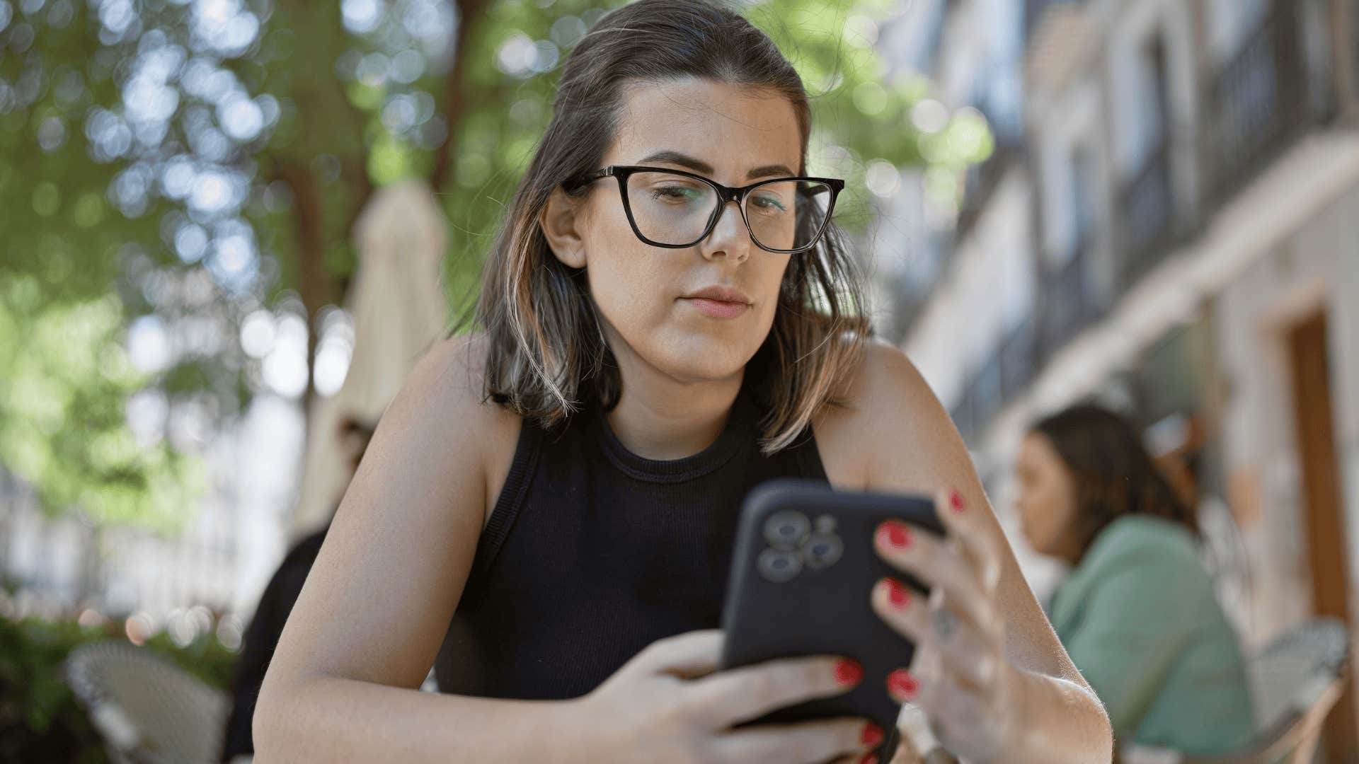 Serious woman thinking I told you so while looking at her phone at a coffee shop