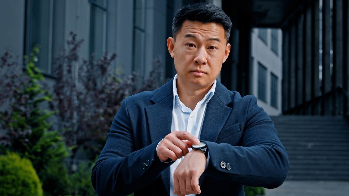 frustrated employee pointing to watch after wasted time