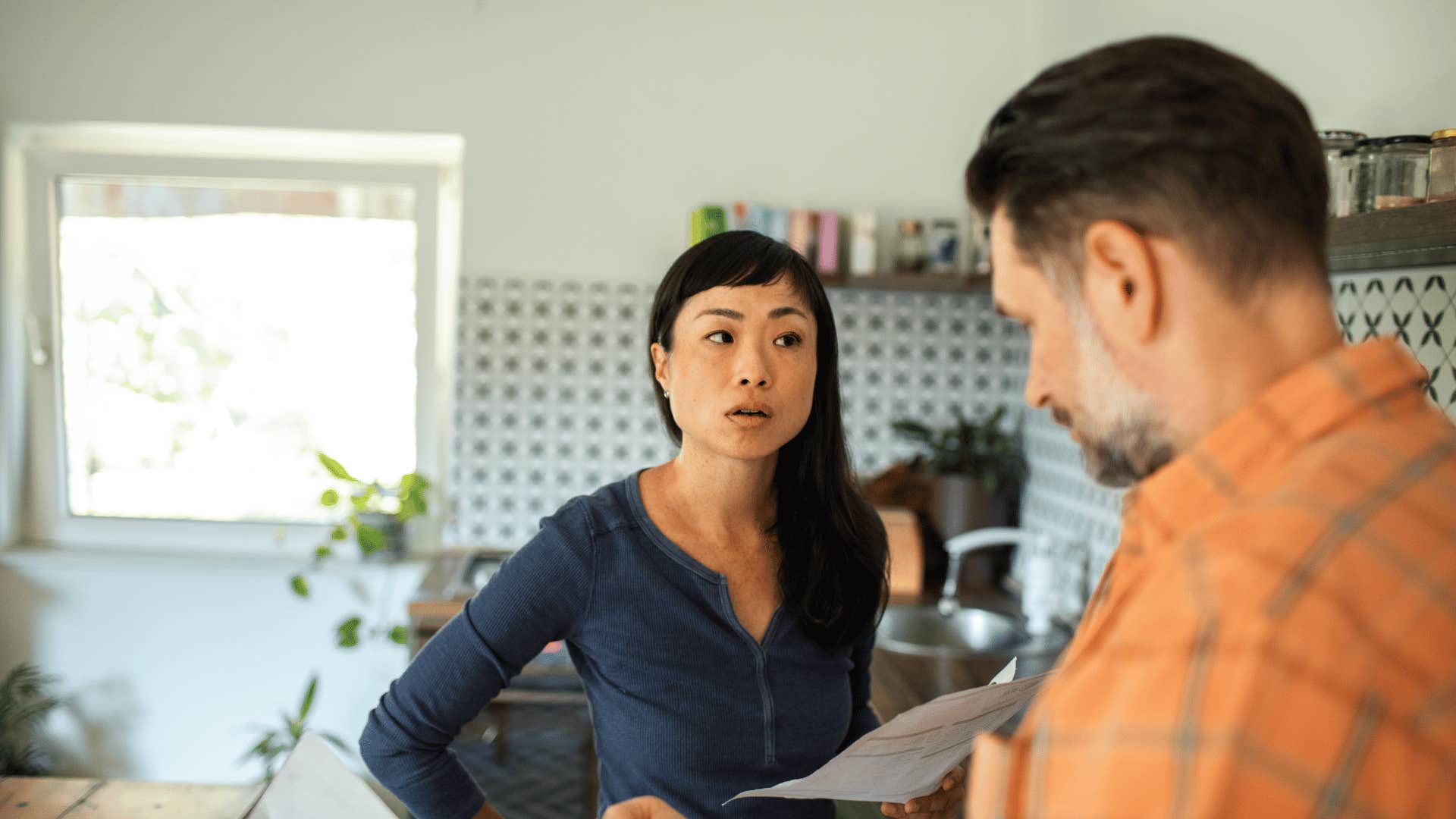 woman arguing with man in kitchen over bill